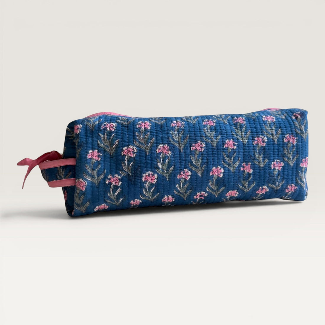 The Block & Bloom navy quilted hair tool organizer bag with pink carnation floral print and pink zipper detail.