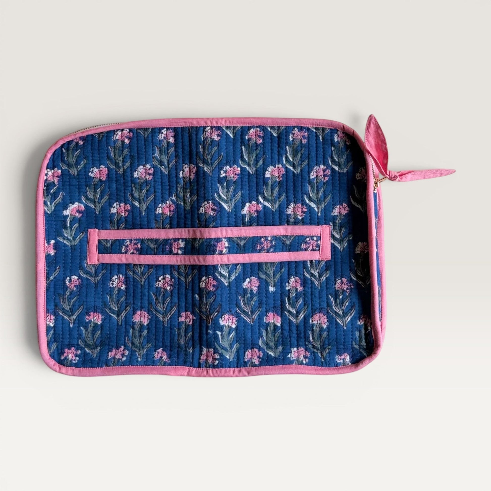 The Block & Bloom navy quilted laptop sleeve with pink carnation floral print, pink trim, and back hand strap.