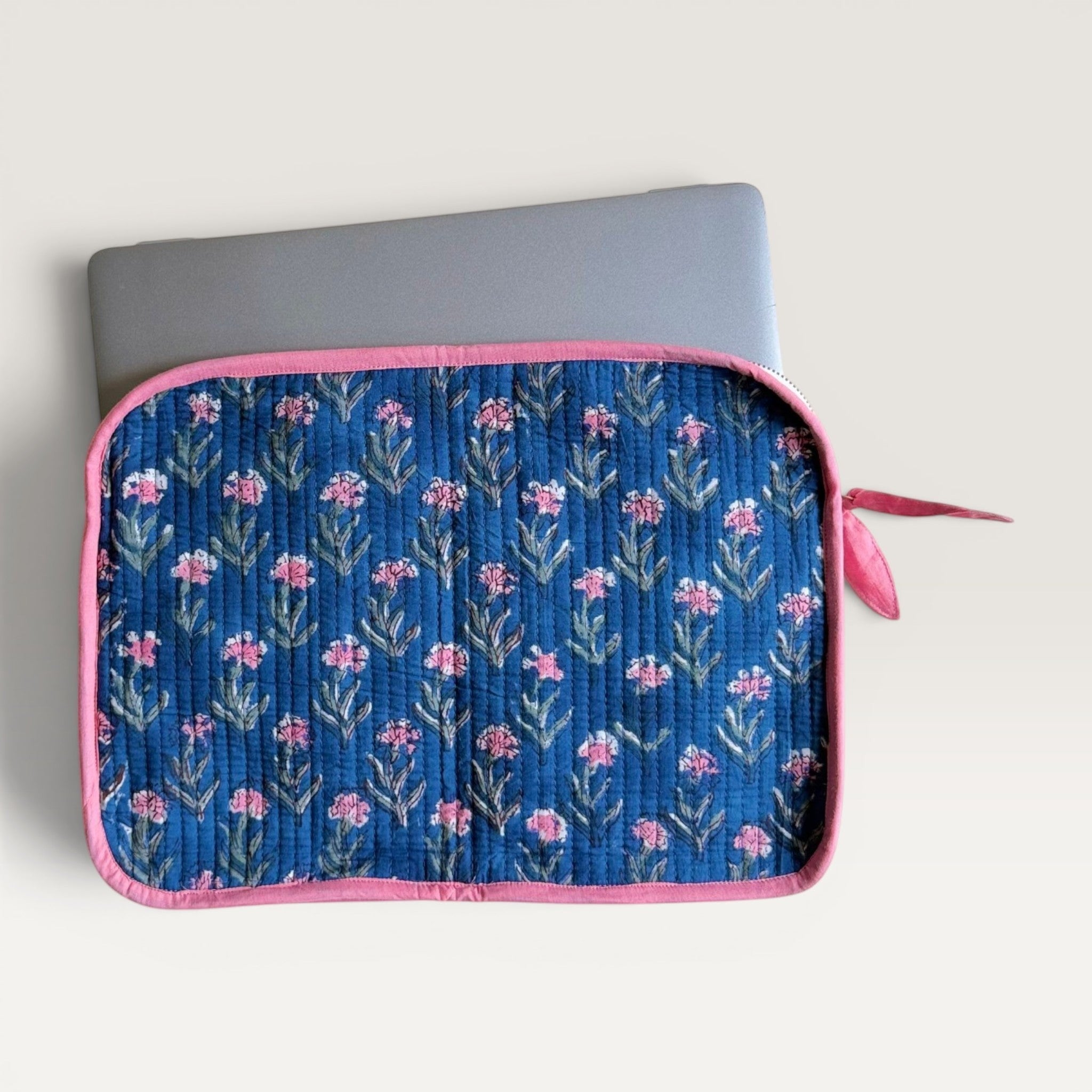 The Block & Bloom navy blue quilted laptop sleeve with pink carnation floral print and a pink fabric bow zipper pull.