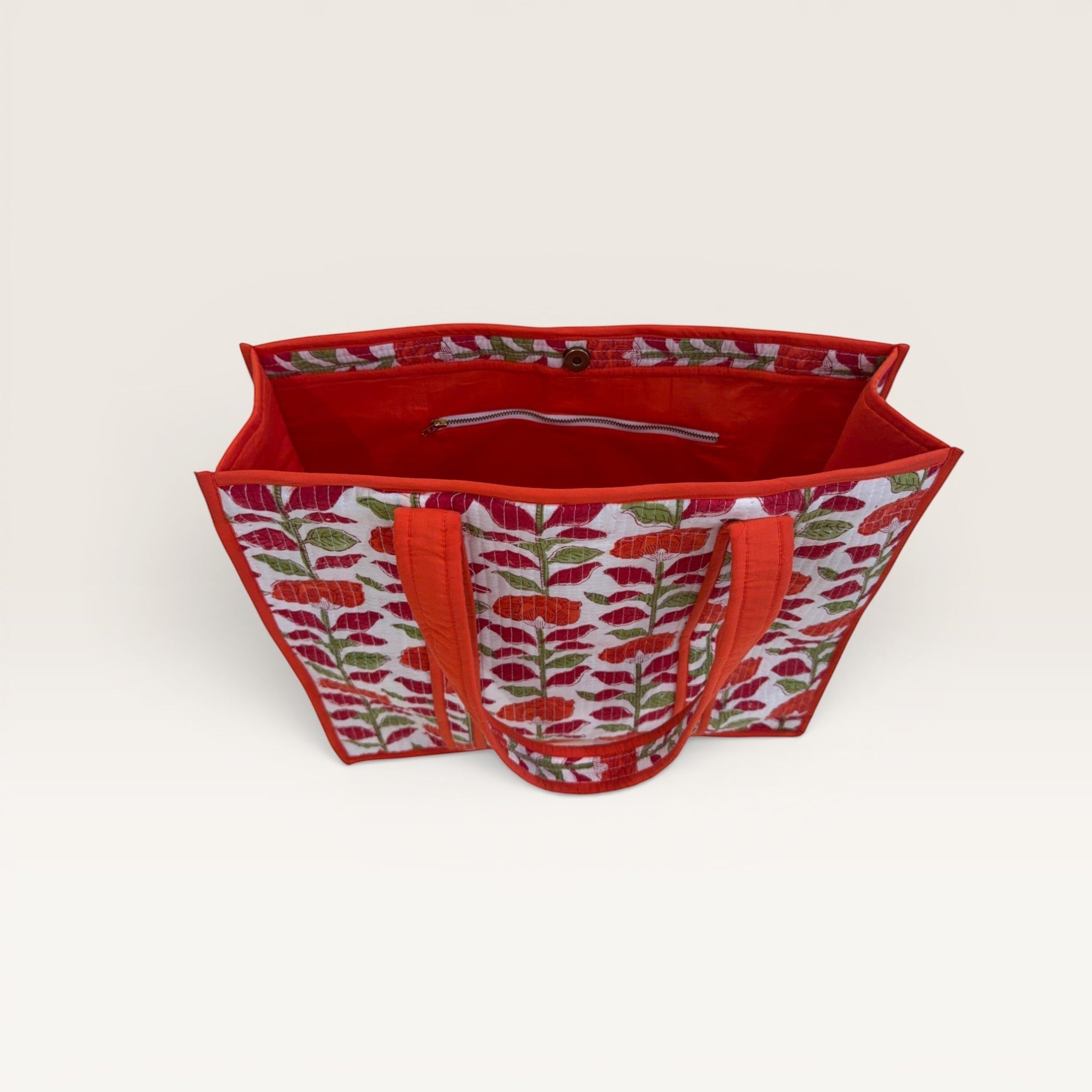 The Block & Bloom orange carnation quilted tote bag with floral print, red interior, and structured base.