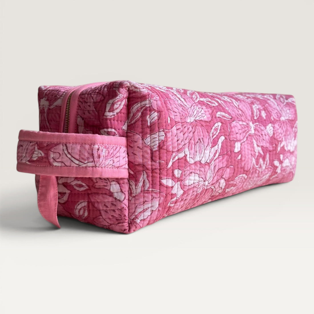 The Block & Bloom quilted hair tool organizer bag in pink and white floral lily print with a secure zipper closure.