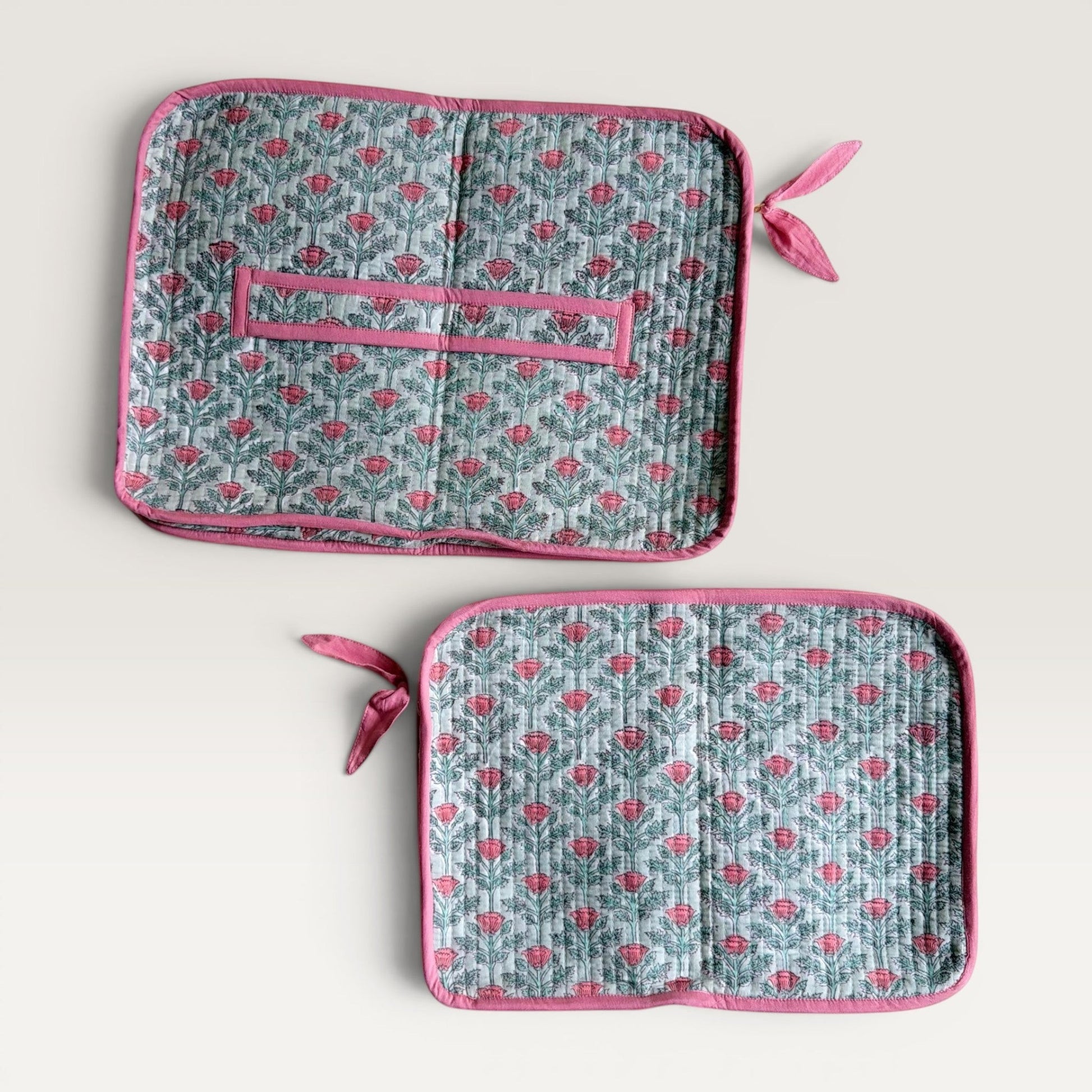 The Block & Bloom quilted laptop sleeve in sage green with pink floral vine print, featuring a back carry strap and bow.