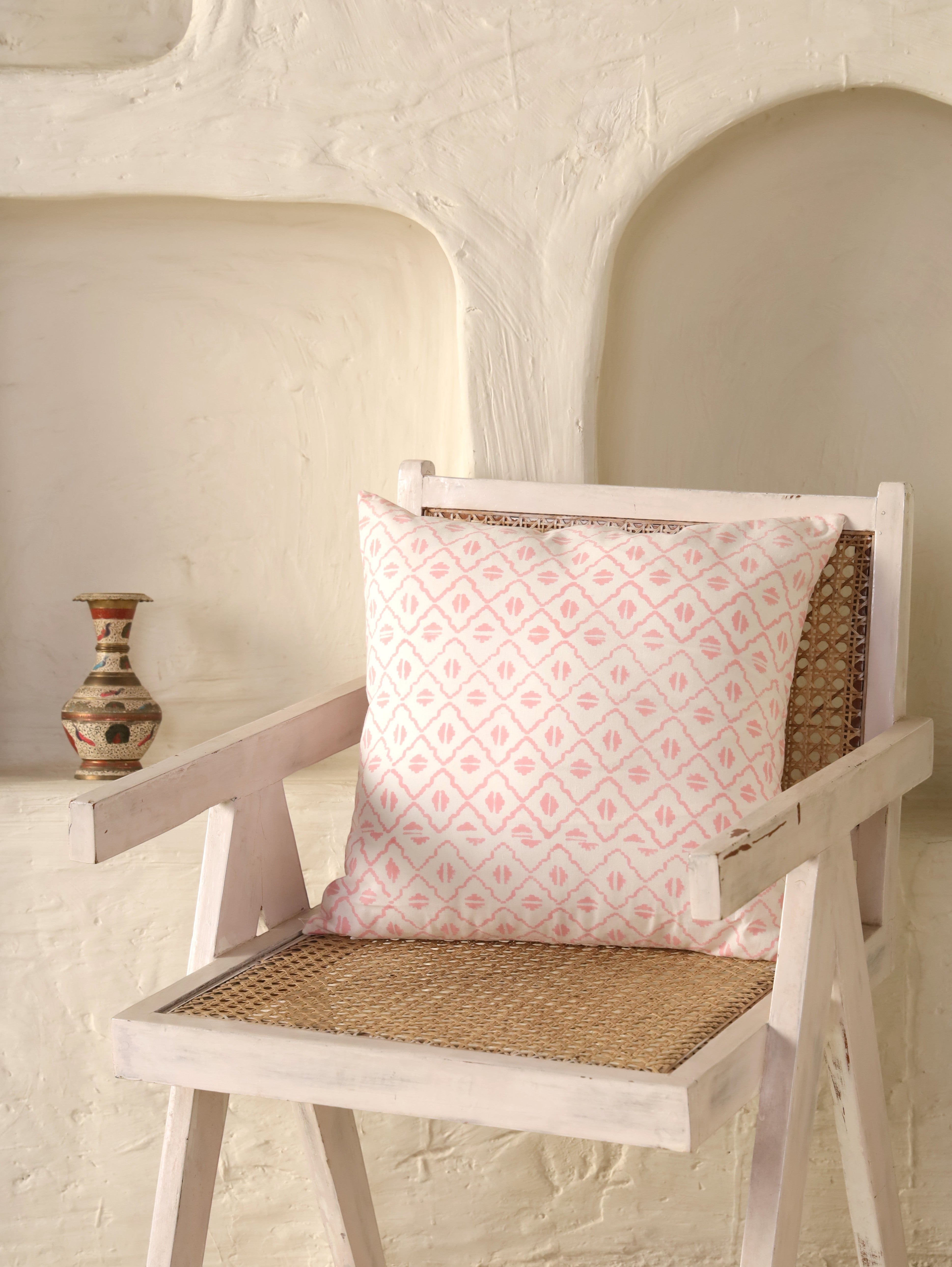 The Block & Bloom pink and ivory cotton cushion cover with a hand-blocked geometric diamond lattice pattern on a chair