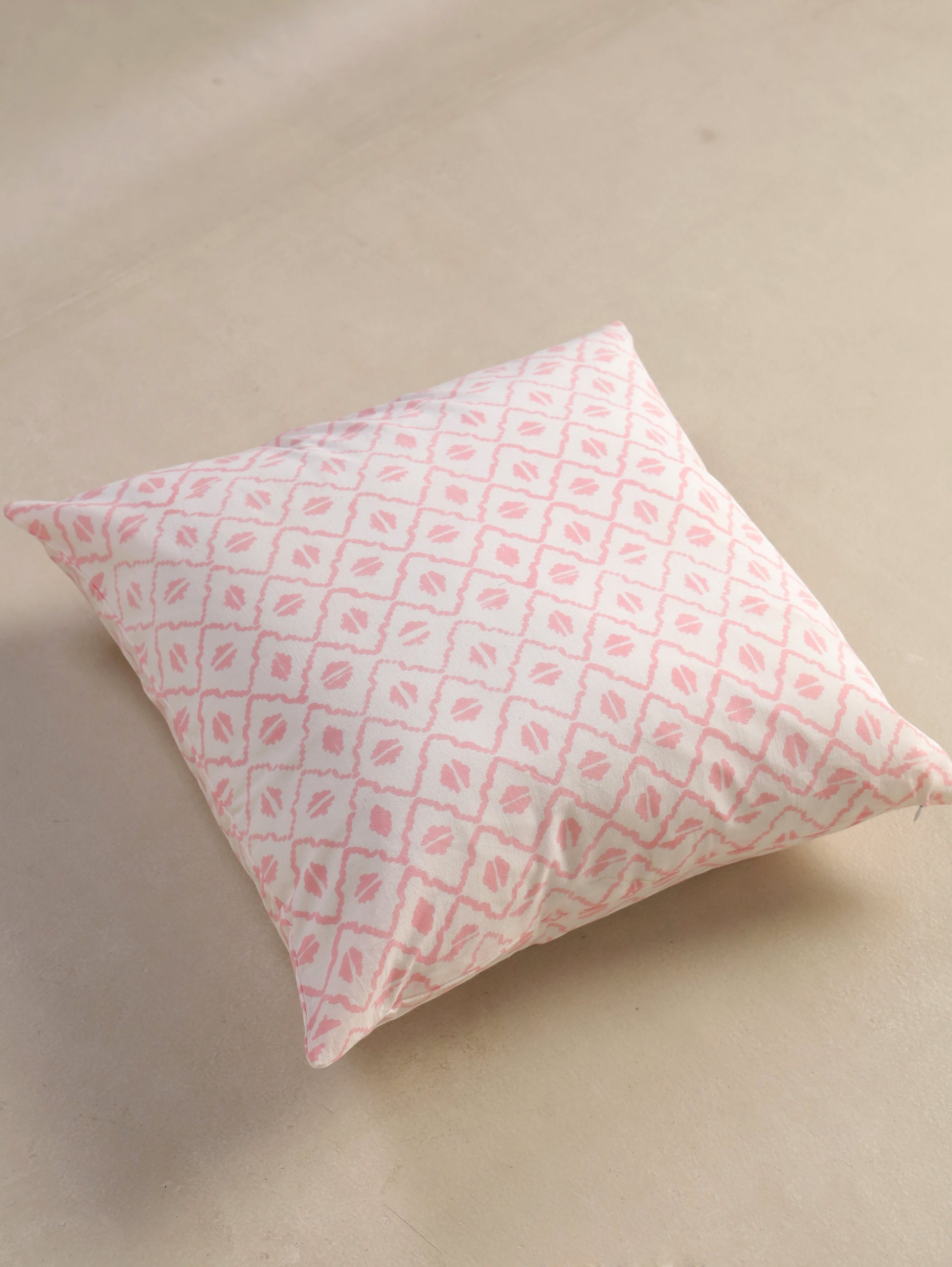 The Block & Bloom pink and ivory cotton cushion cover featuring a hand-block printed geometric diamond lattice pattern.