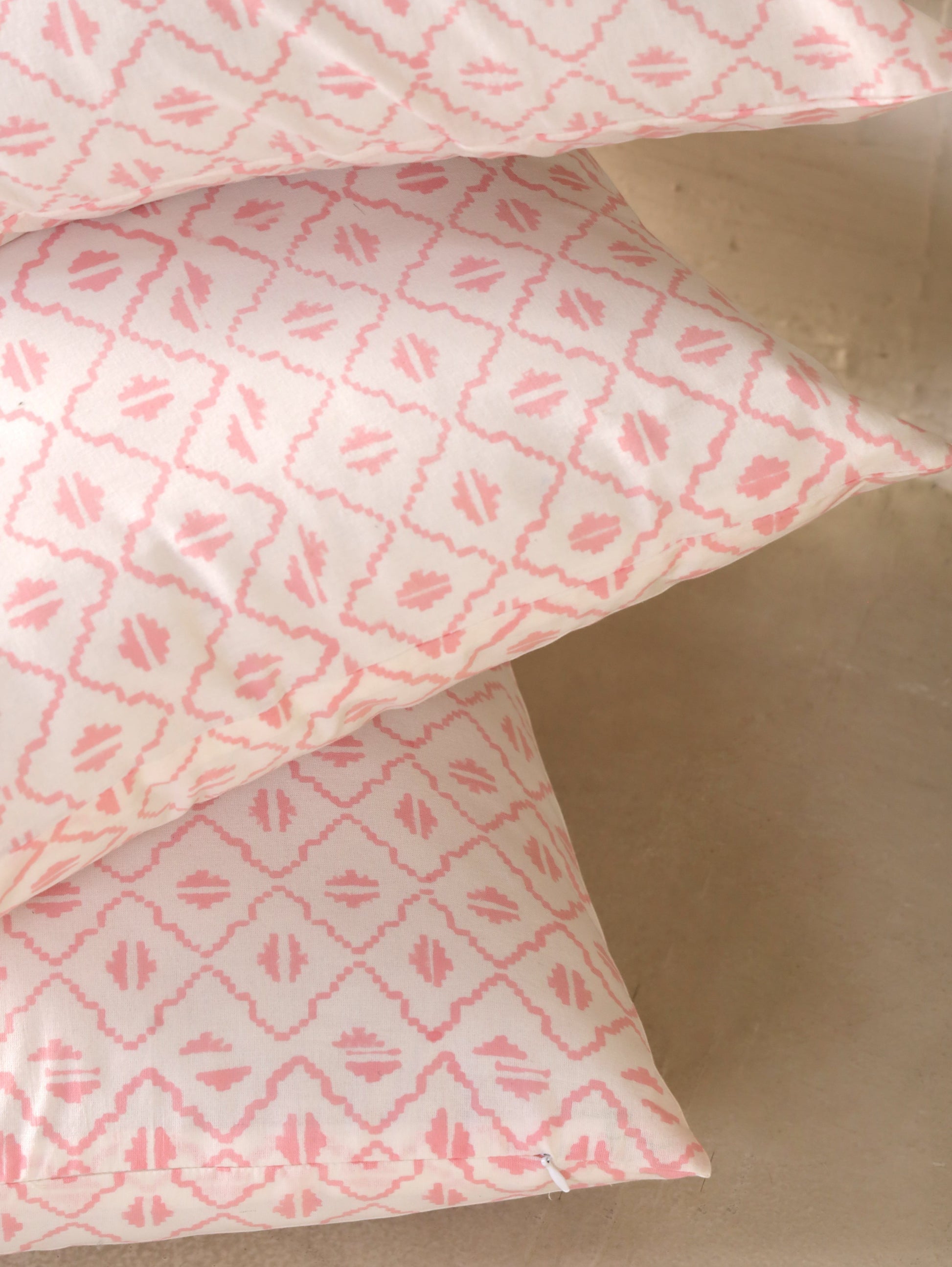 The Block & Bloom pink and ivory cotton cushion cover with a hand-block printed geometric diamond and seed motif.