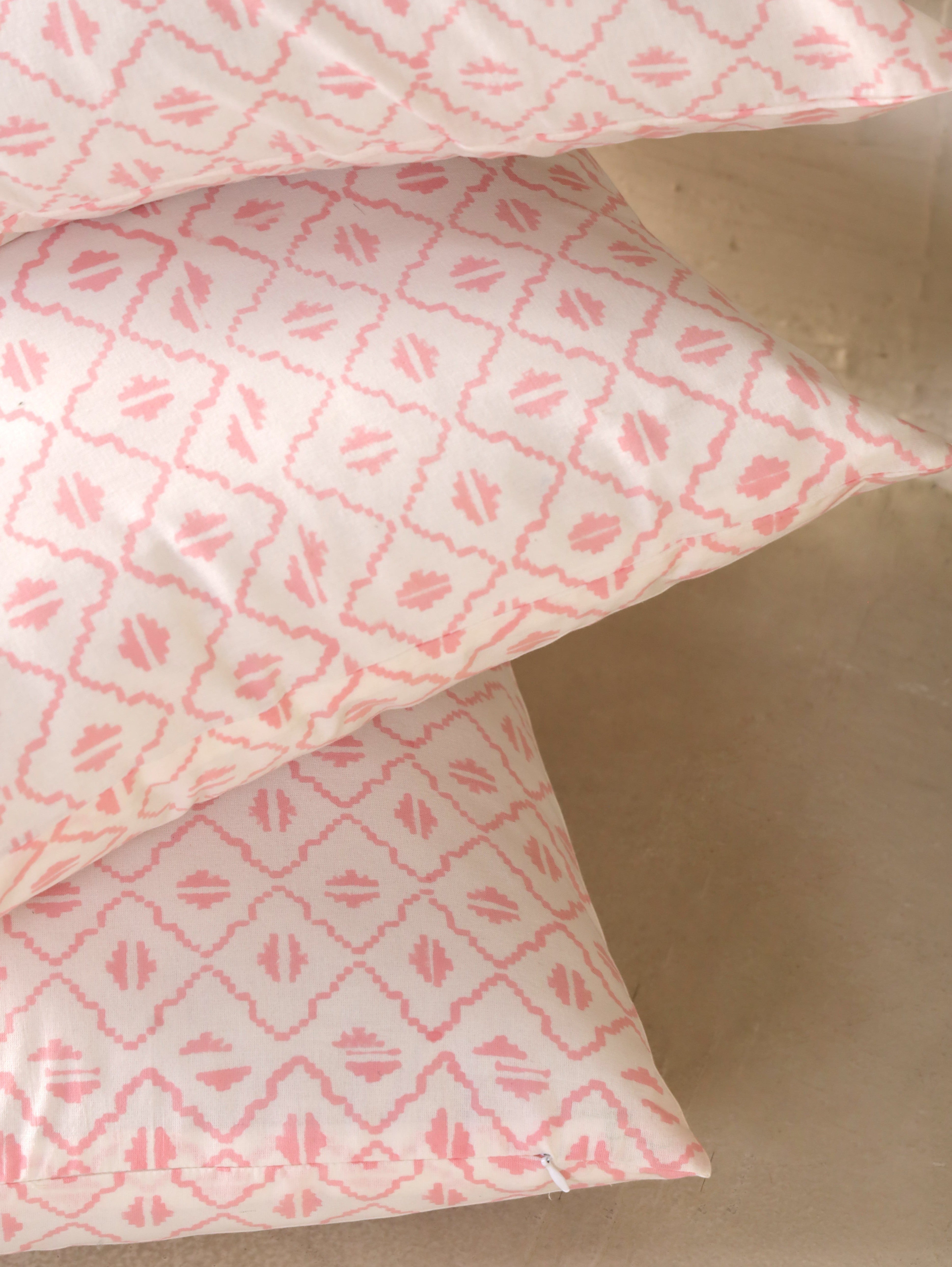 The Block & Bloom pink and ivory cotton cushion cover with a hand-block printed geometric diamond and seed motif.