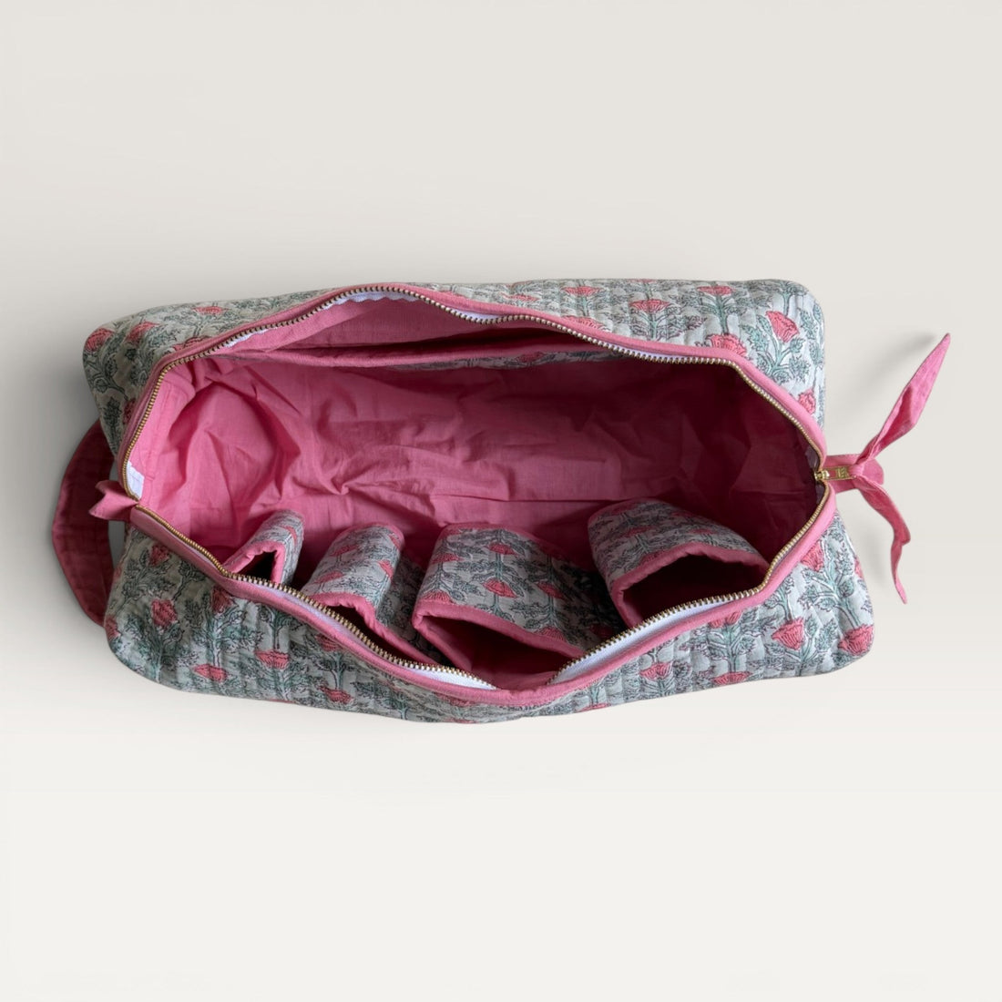 The Block & Bloom quilted hair tool organizer bag in sage green with a pink floral vine print and secure zipper closure.