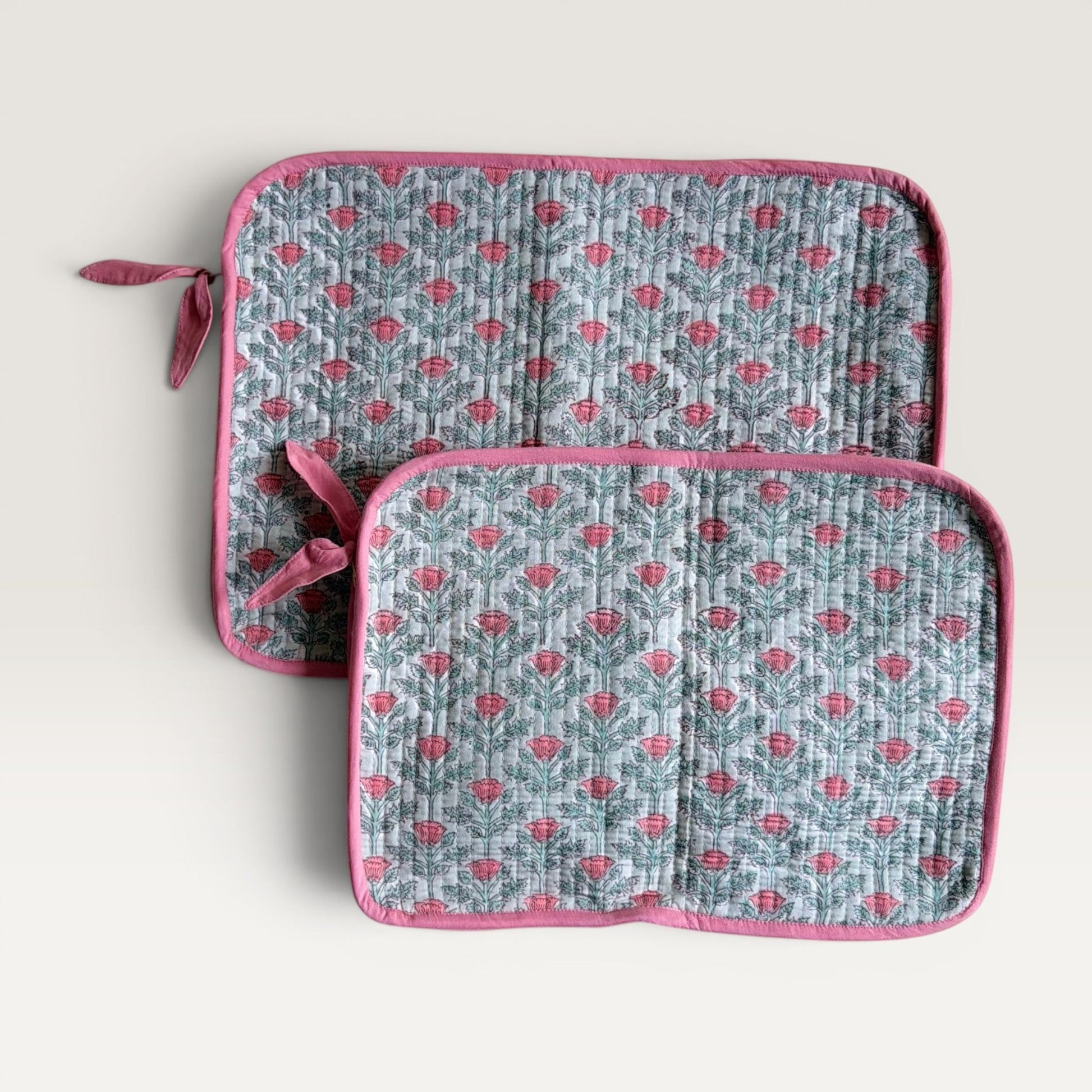 The Block & Bloom quilted laptop sleeve in sage green with pink floral vine print and fabric bow zipper detail.