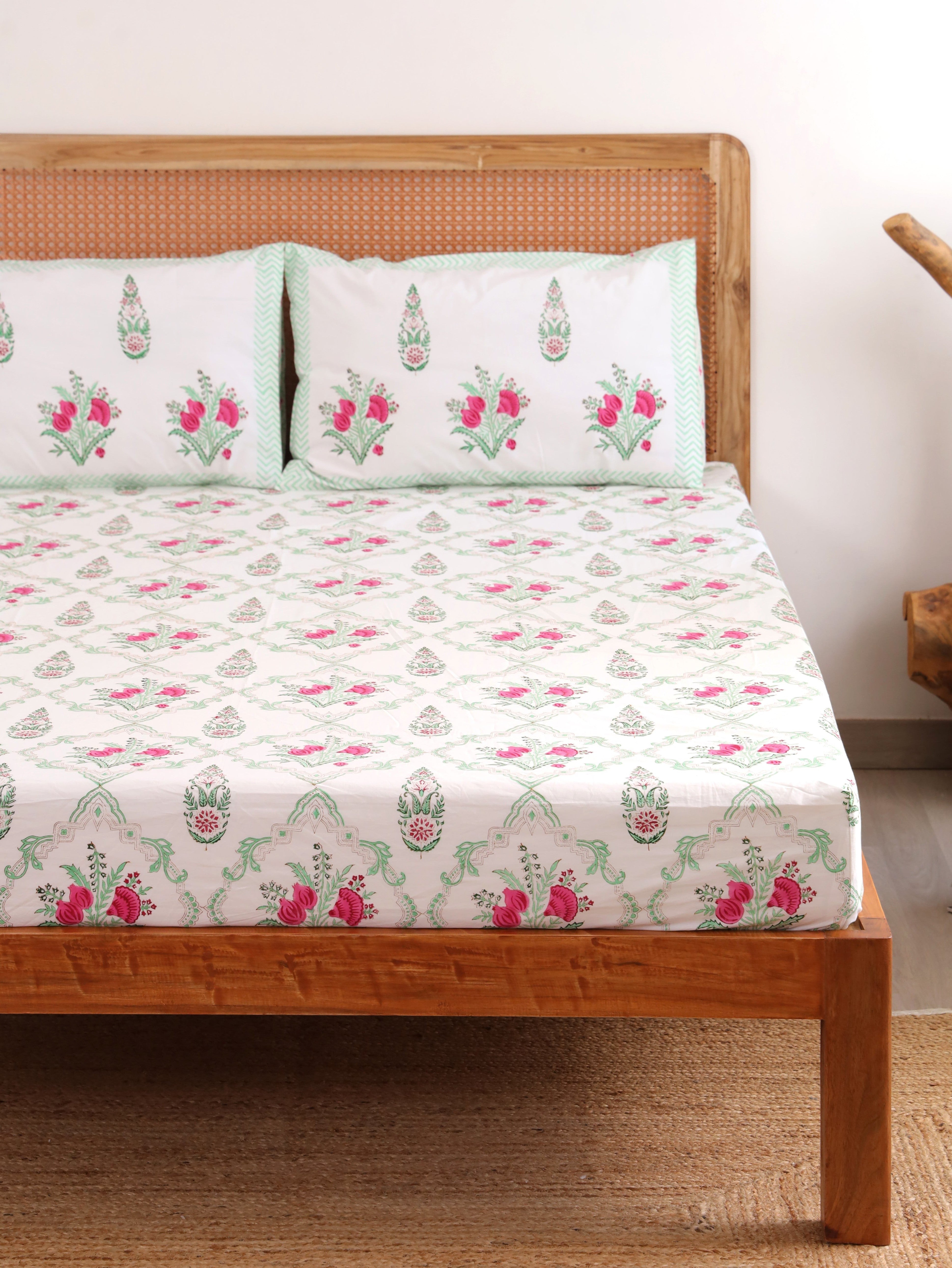 The Block & Bloom Pomegranate Meadow cotton fitted sheet and pillowcases with pink floral print on a white background.