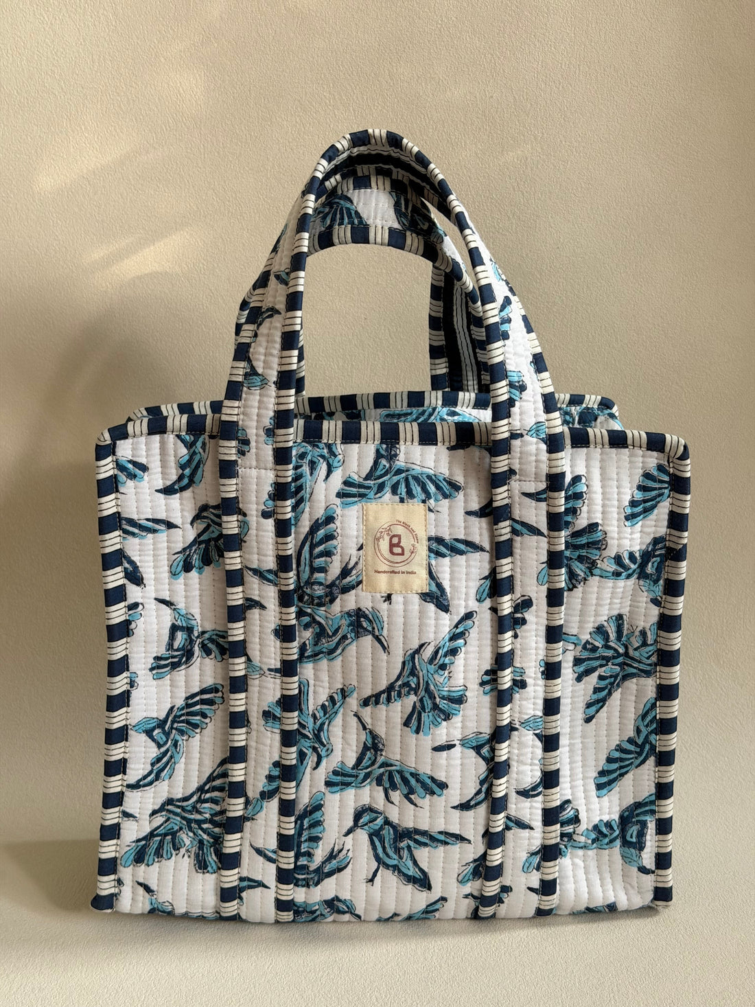 The Block & Bloom quilted mini tote featuring a blue bird hand block print on white fabric with striped trim.