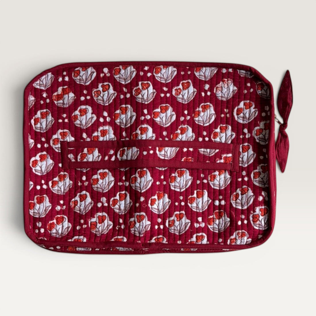 The Block & Bloom quilted laptop sleeve in burgundy red with red tulip motifs, white dots, and a fabric bow zipper.