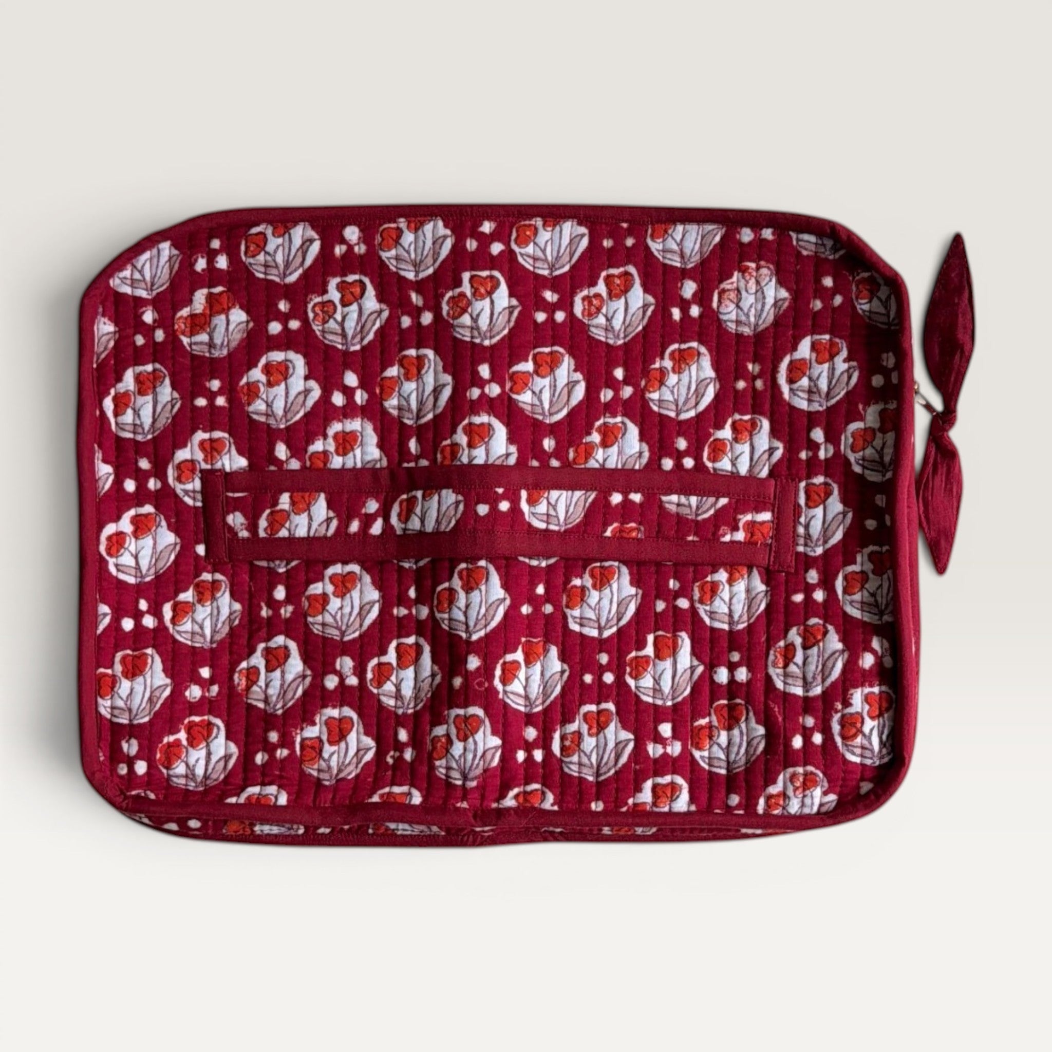 The Block & Bloom quilted burgundy laptop sleeve with red tulip motifs, white dot accents, and a fabric bow zipper.