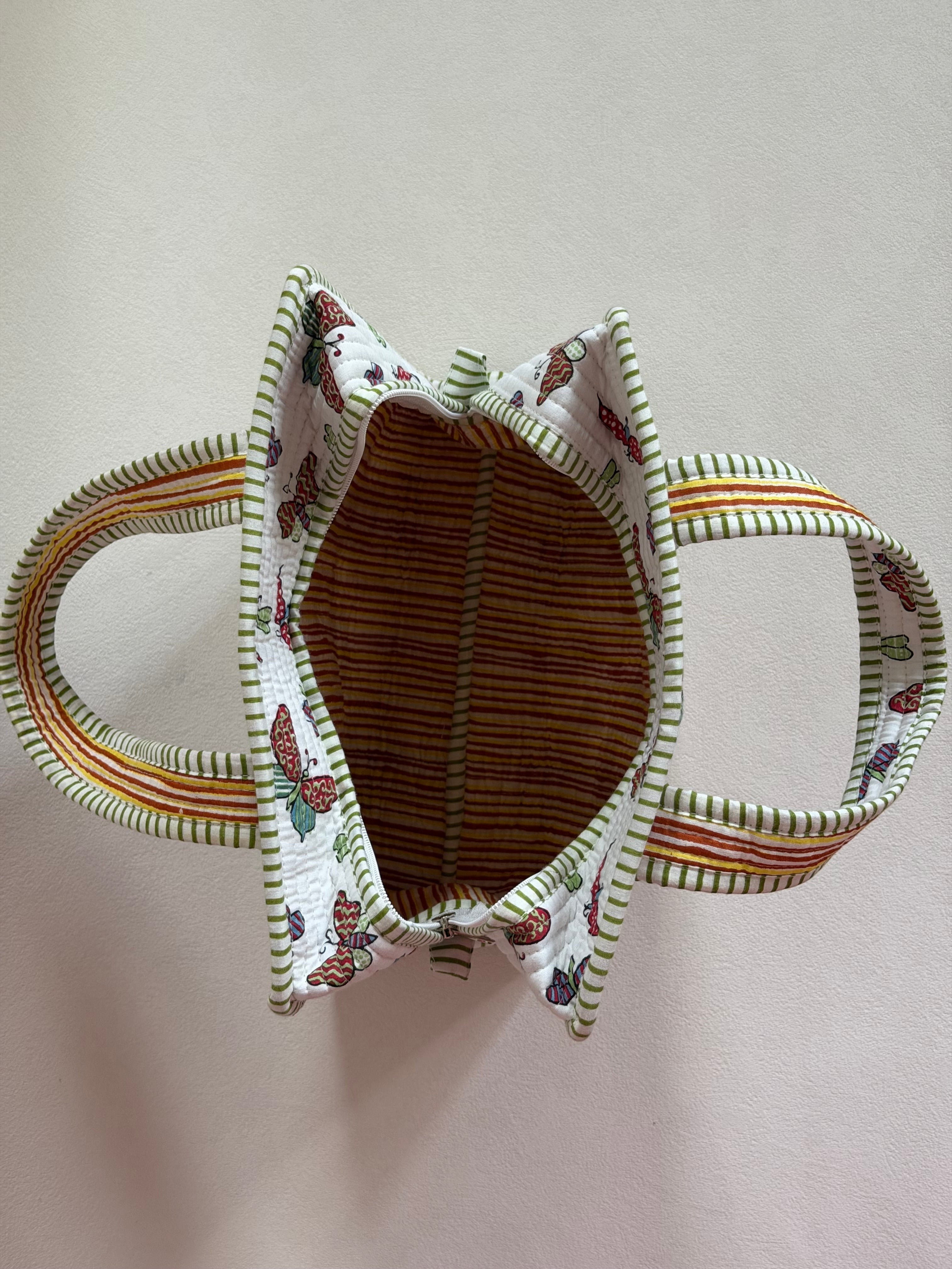 The Block & Bloom butterfly quilted mini tote bag with green striped handles and interior lining, top-down view.