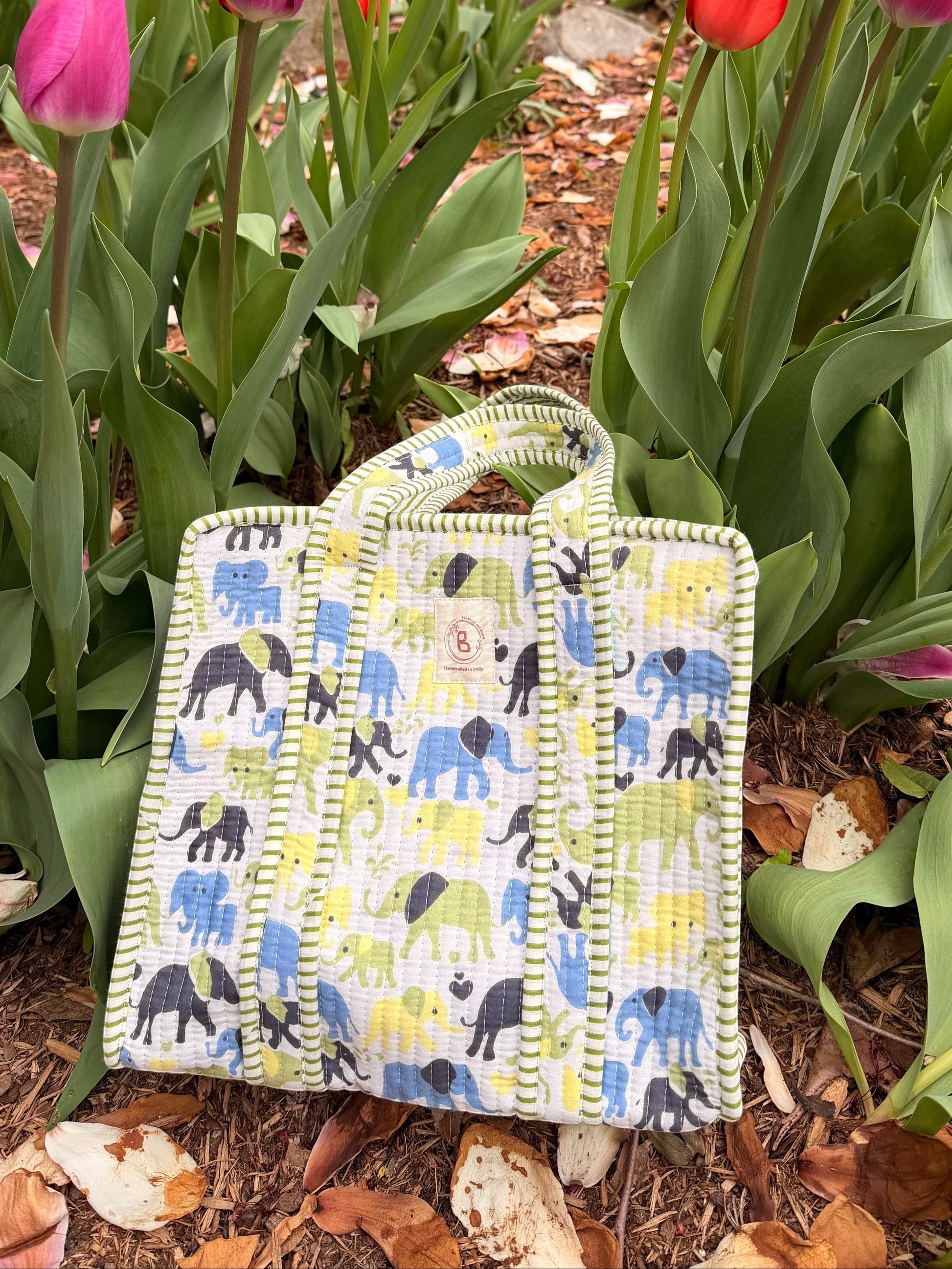 The Block & Bloom quilted mini tote featuring a colourful elephant print on a white background in a garden setting.