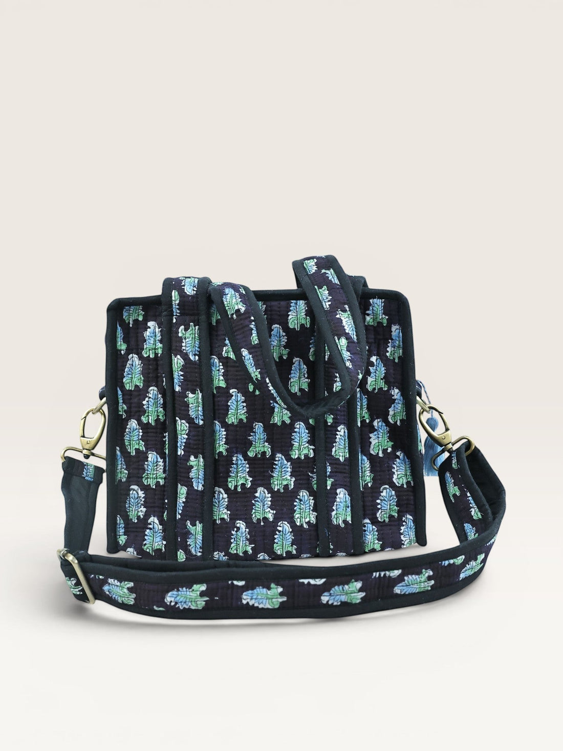 The Block & Bloom Midnight Fern quilted mini tote bag in black with blue and sage green leaf print and brass hardware.