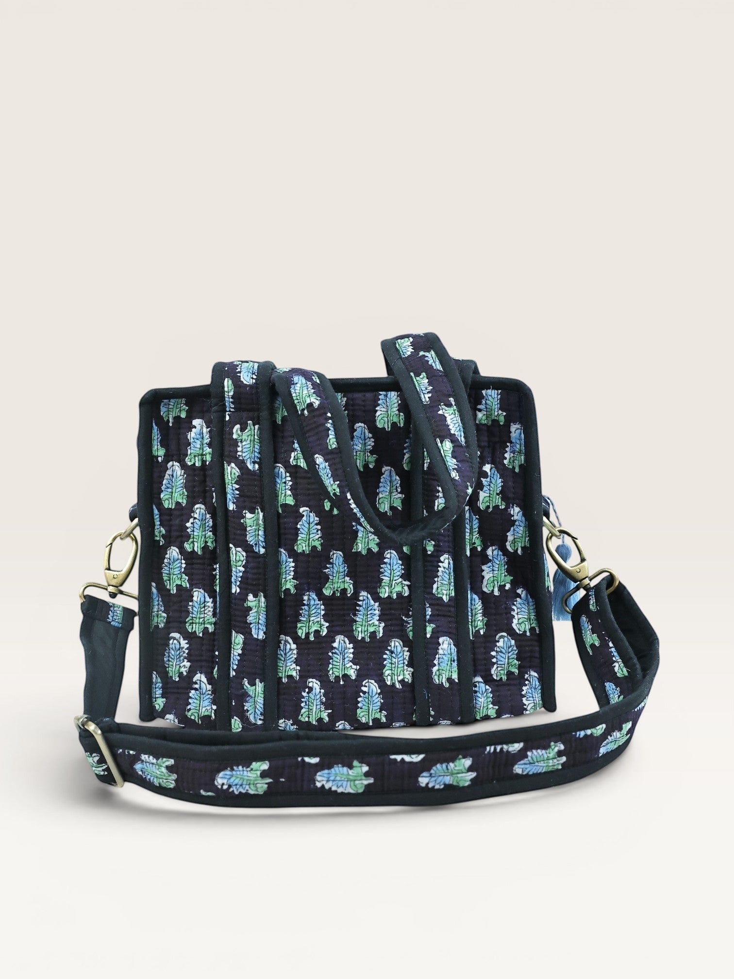 The Block & Bloom Midnight Fern quilted mini tote bag in black with blue and sage green leaf print and brass hardware.
