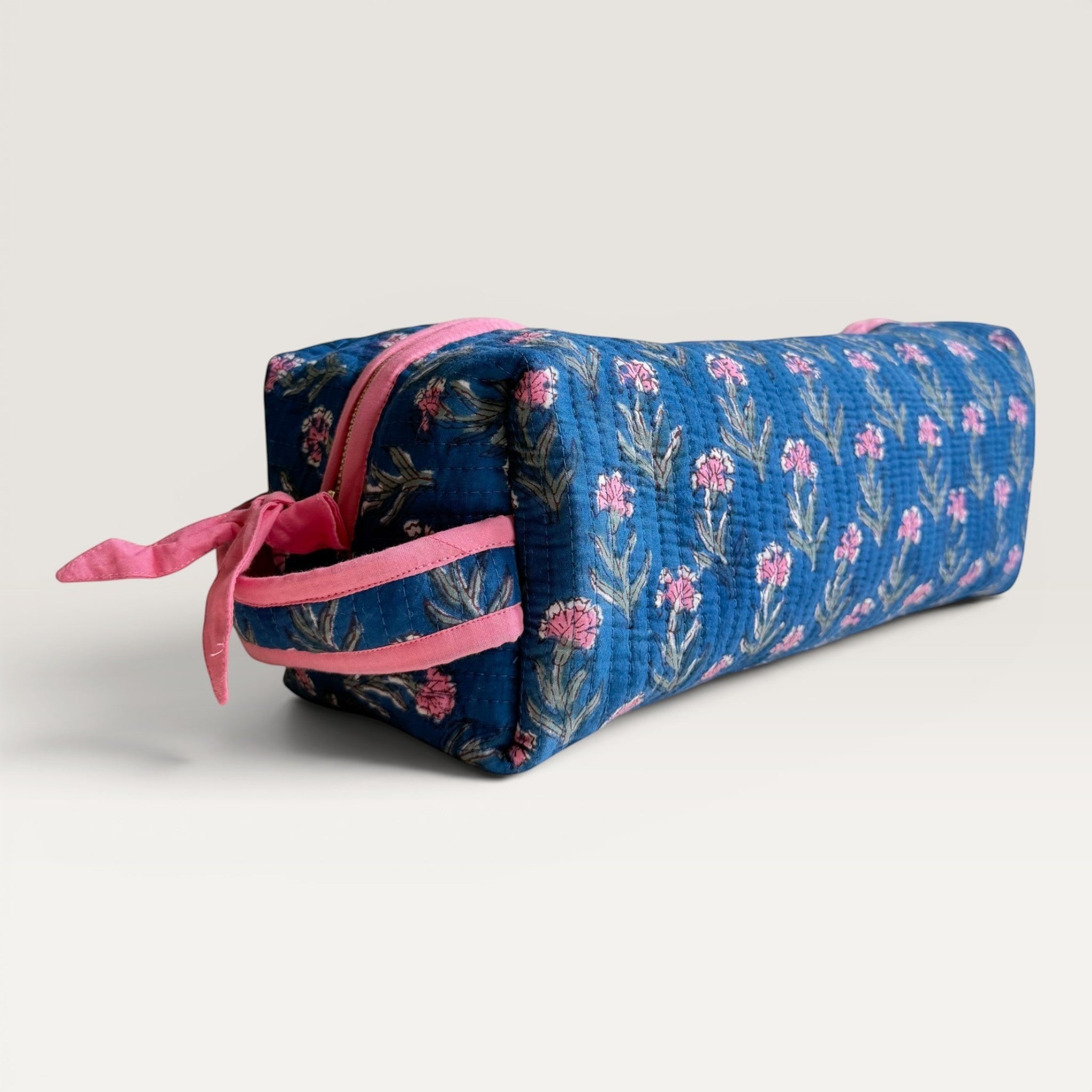 The Block & Bloom quilted navy blue hair tool organizer bag with pink carnation floral print and pink zipper details.