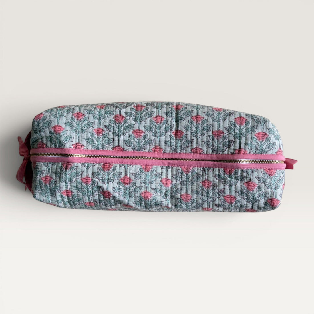 The Block & Bloom quilted hair tool organizer bag in sage green with a pink floral vine print and secure zipper closure.