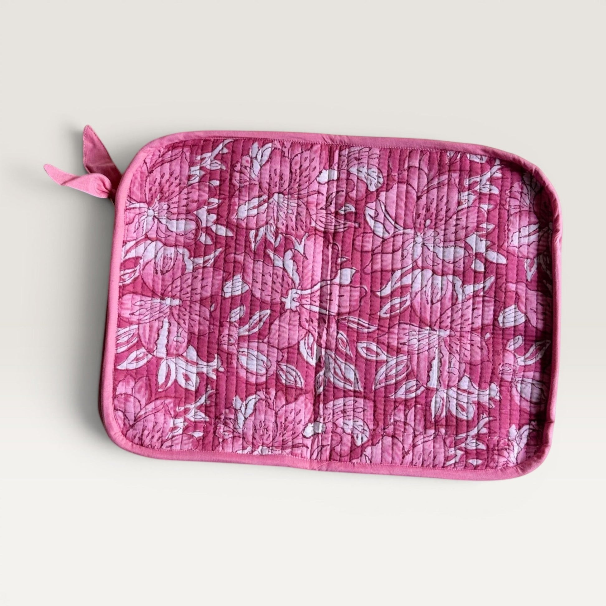 The Block & Bloom quilted laptop sleeve featuring a pink and white lily floral print with a fabric bow zipper pull.