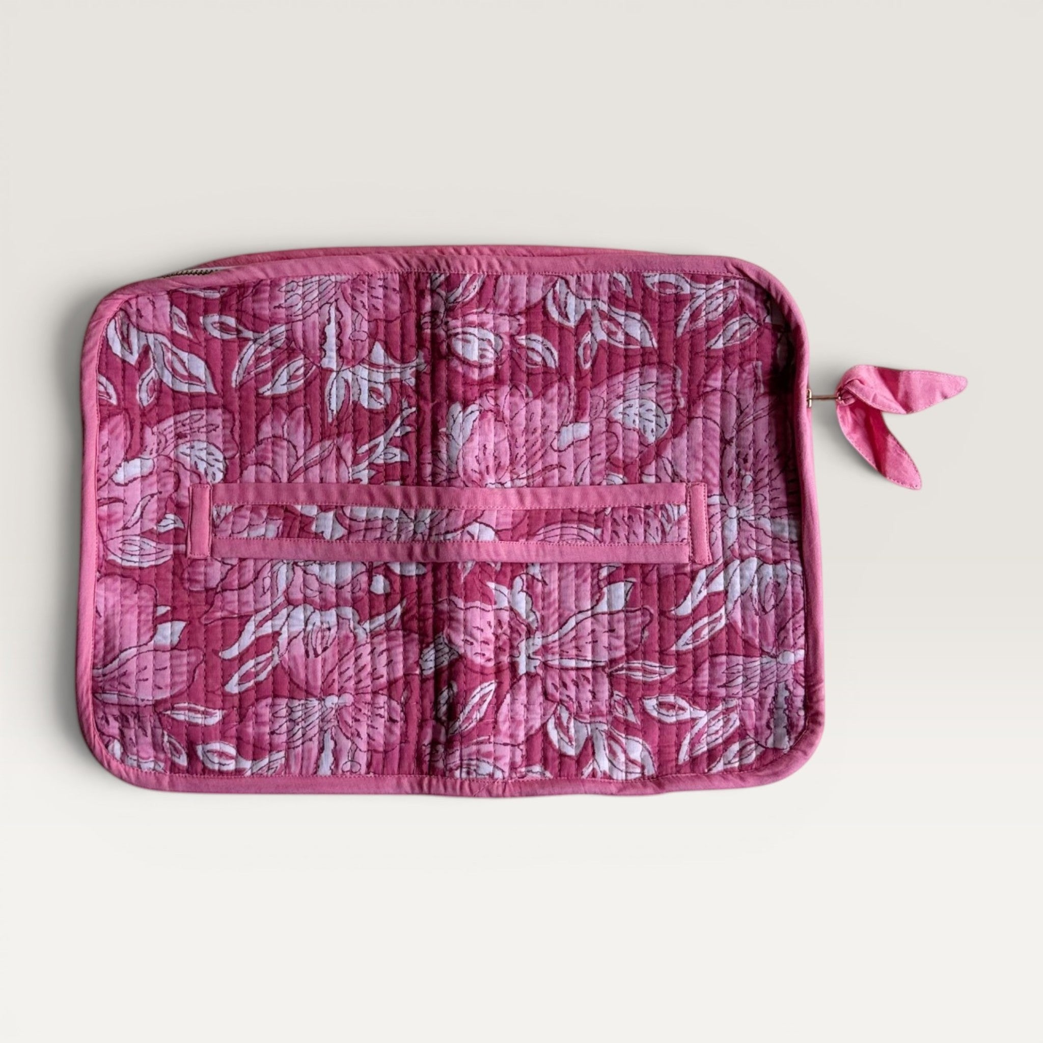 The Block & Bloom quilted laptop sleeve in deep pink and white lily floral print with a fabric bow zipper pull.