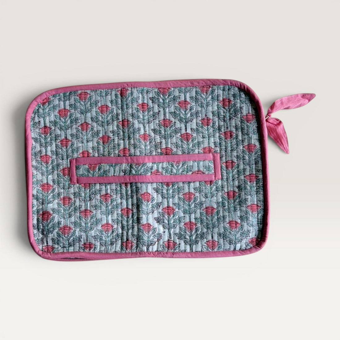 The Block & Bloom quilted laptop sleeve in sage green with pink floral vine print and a fabric bow zipper pull.