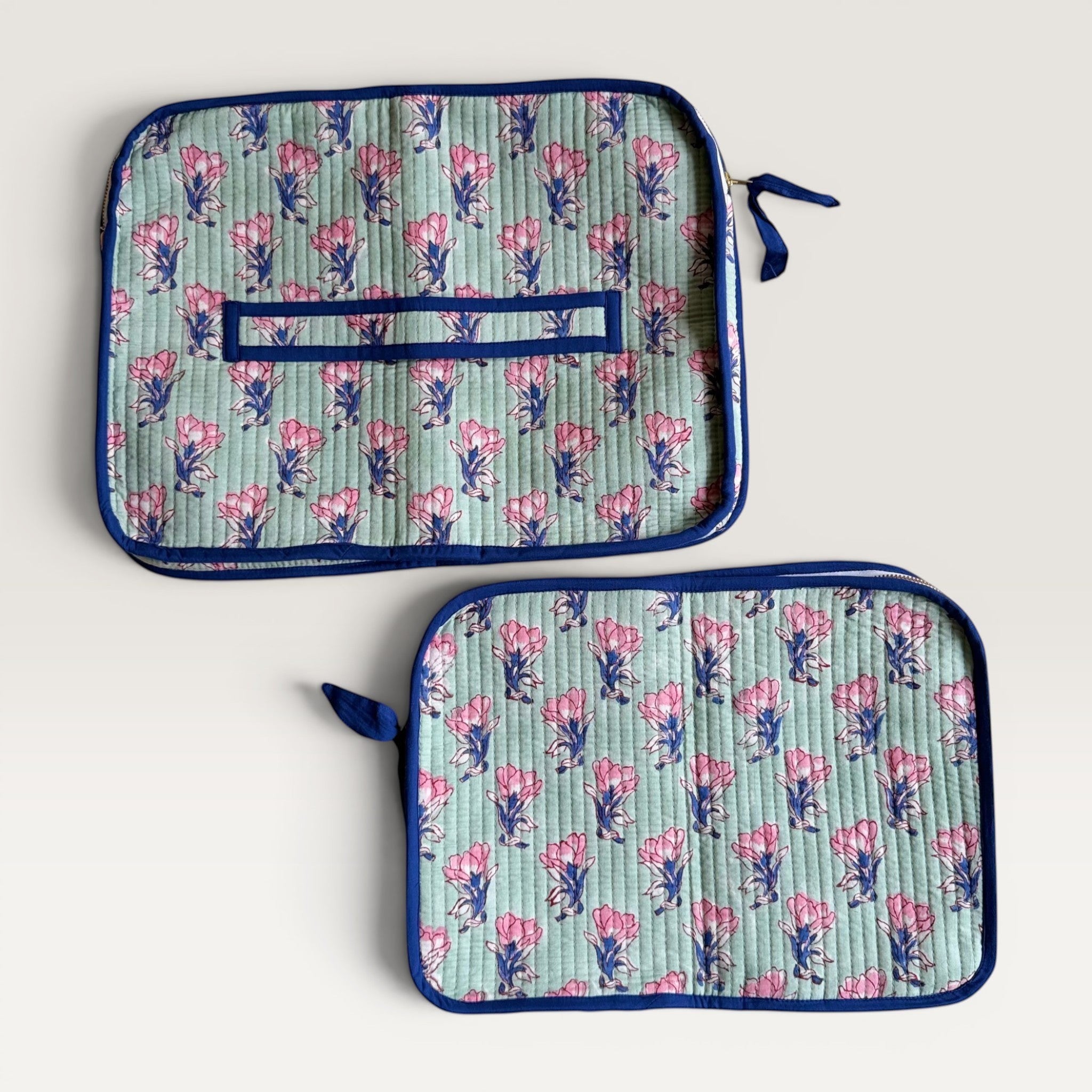 The Block & Bloom quilted laptop sleeve in sage green with pink saffron floral print and navy blue trim.