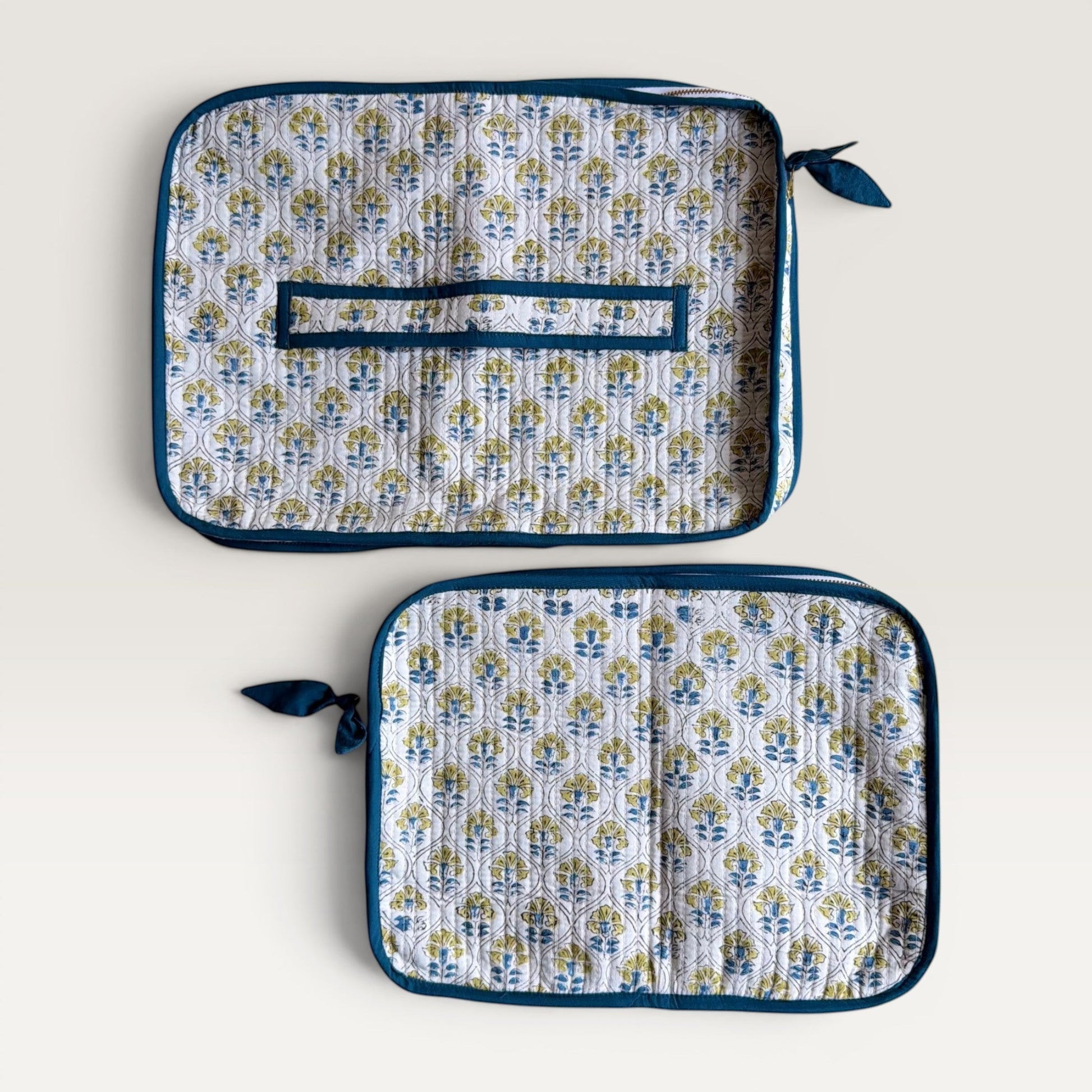 The Block & Bloom quilted laptop sleeve with blue and yellow floral tile pattern on white fabric and hand-stitched bow.