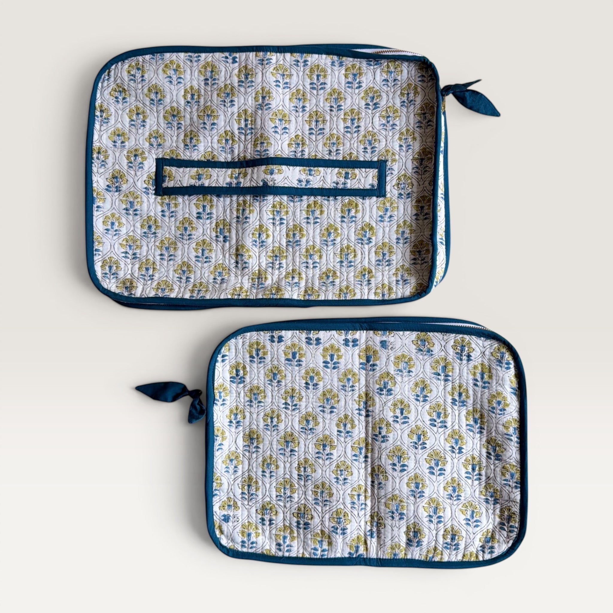 The Block & Bloom quilted laptop sleeve with blue and yellow floral tile pattern on white fabric and hand-stitched bow.