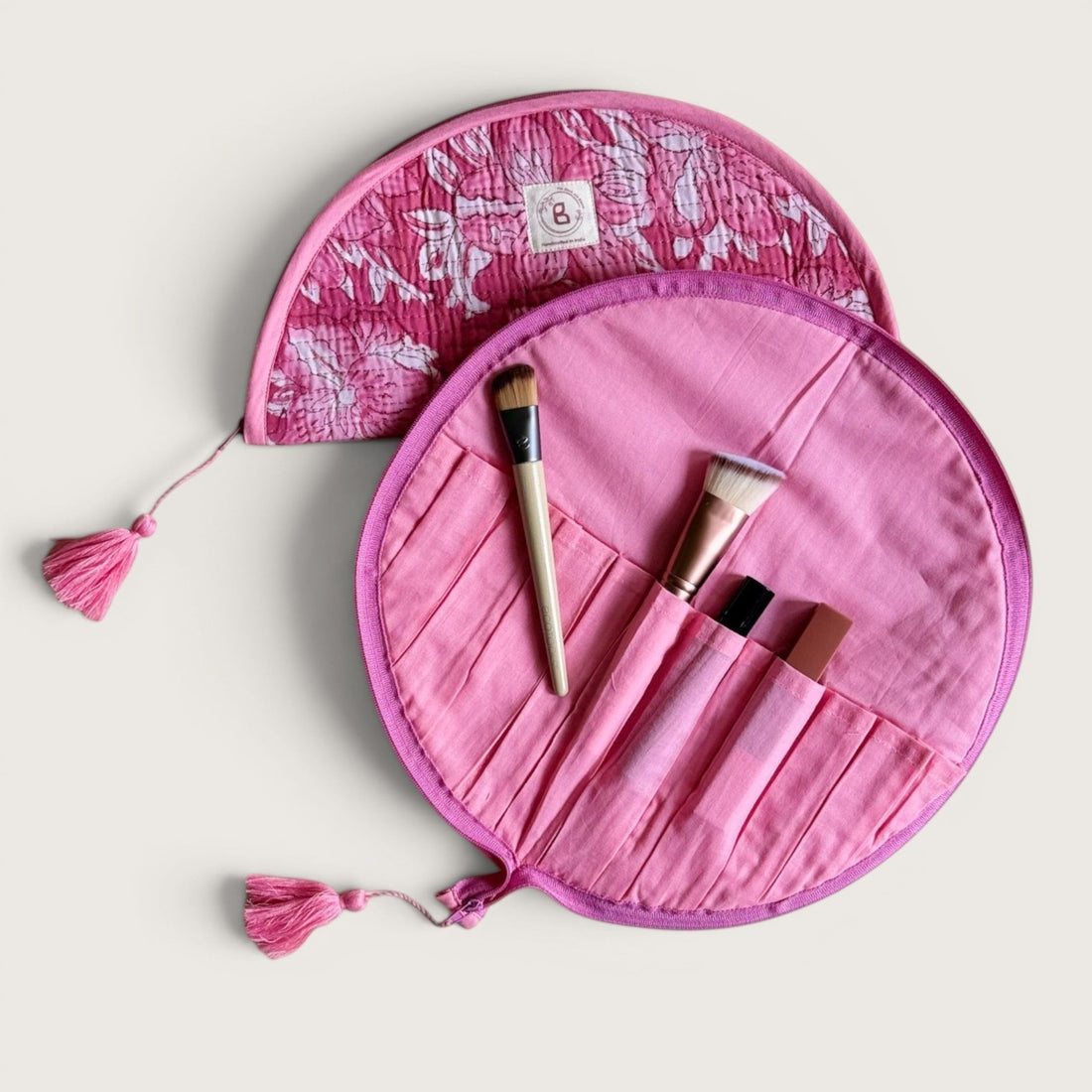 The Block & Bloom quilted makeup brush pouch in pink and white floral cotton with tassel zipper pulls.