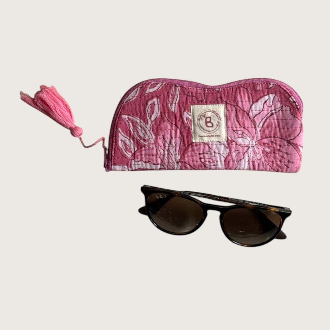 The Block & Bloom quilted cotton sunglasses pouch in pink with a white lily floral print and a decorative tassel.
