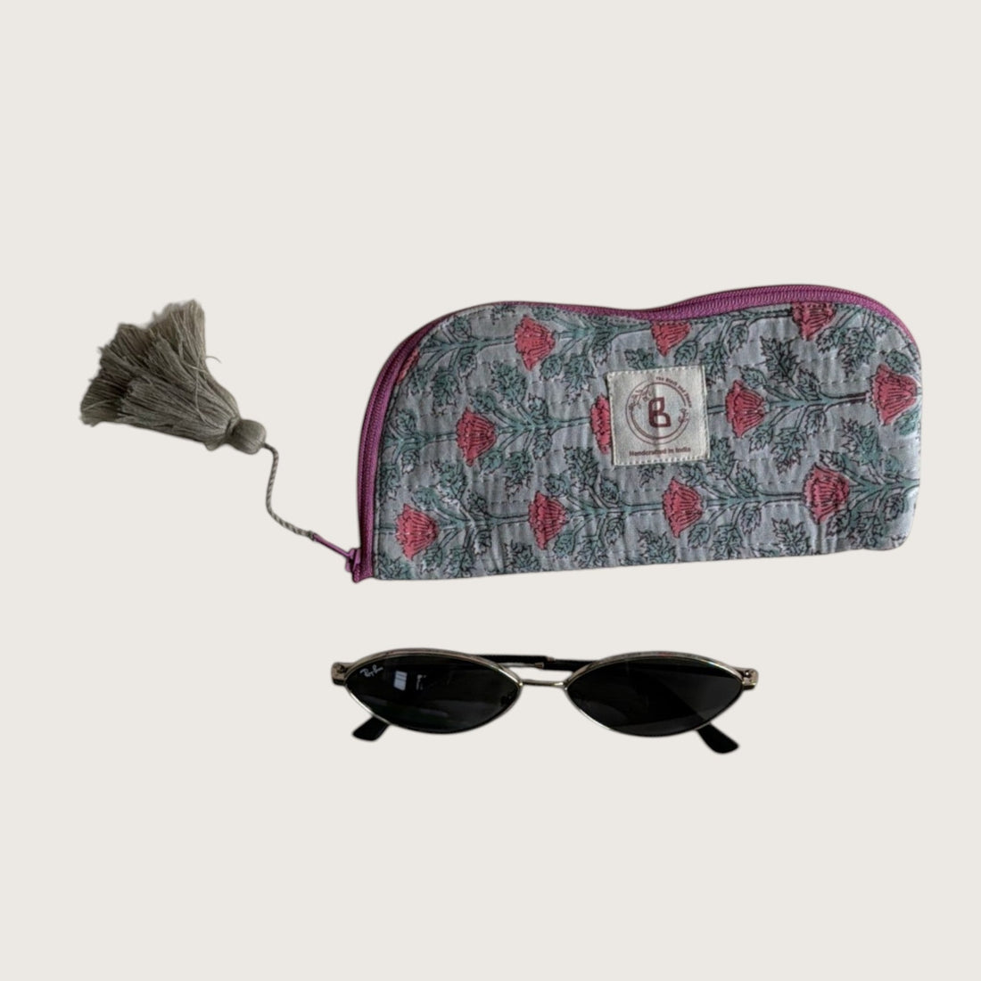 The Block & Bloom quilted cotton sunglasses pouch in sage green with pink floral vine print and a decorative tassel.