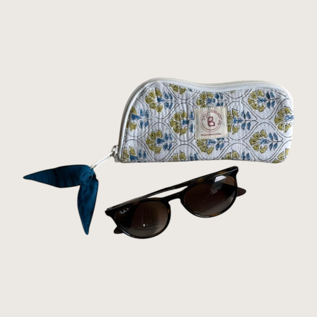 The Block & Bloom quilted cotton sunglasses pouch in white with blue and yellow cosmos floral print and zipper pull.
