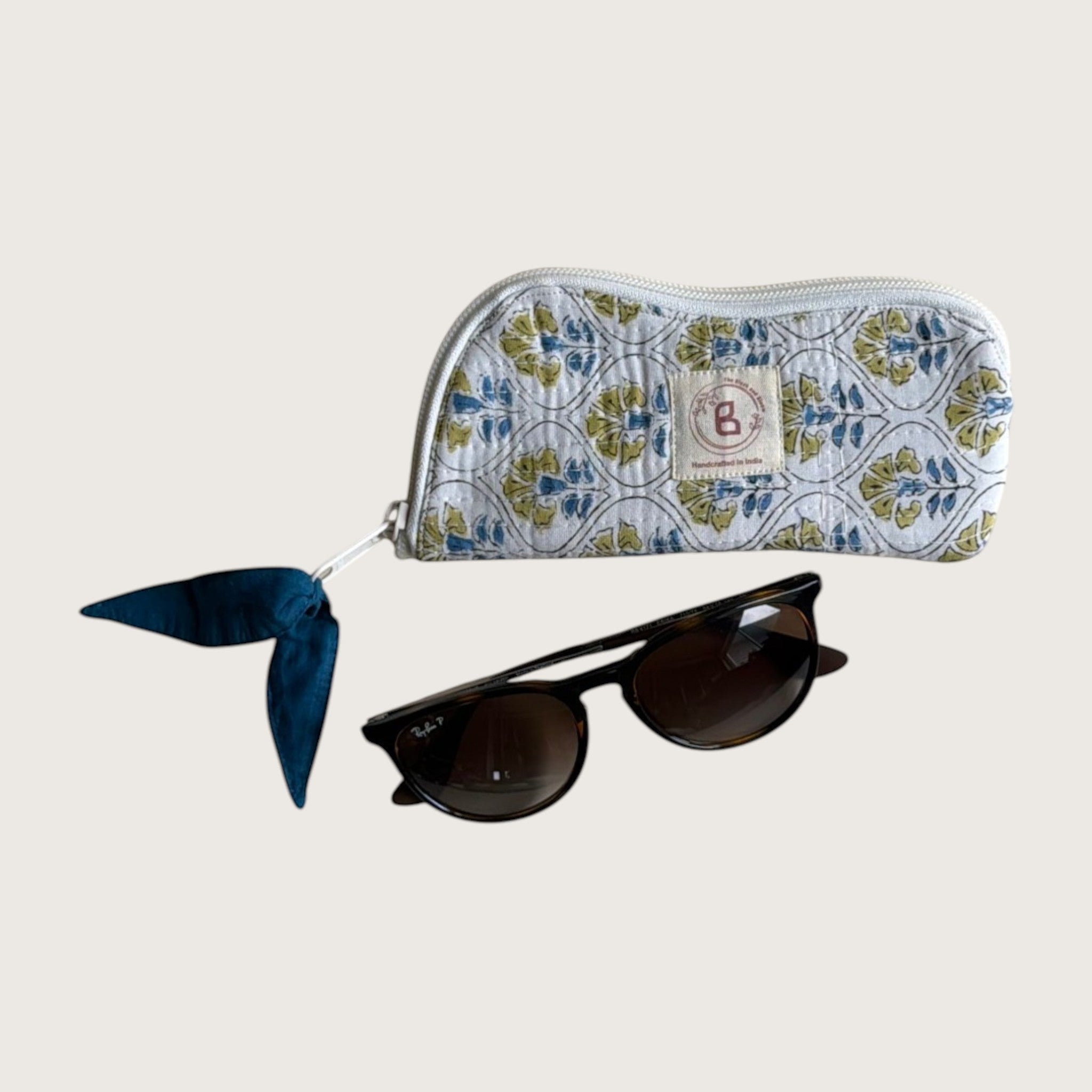 The Block & Bloom quilted cotton sunglasses pouch in white with blue and yellow floral tile print and zipper pull.
