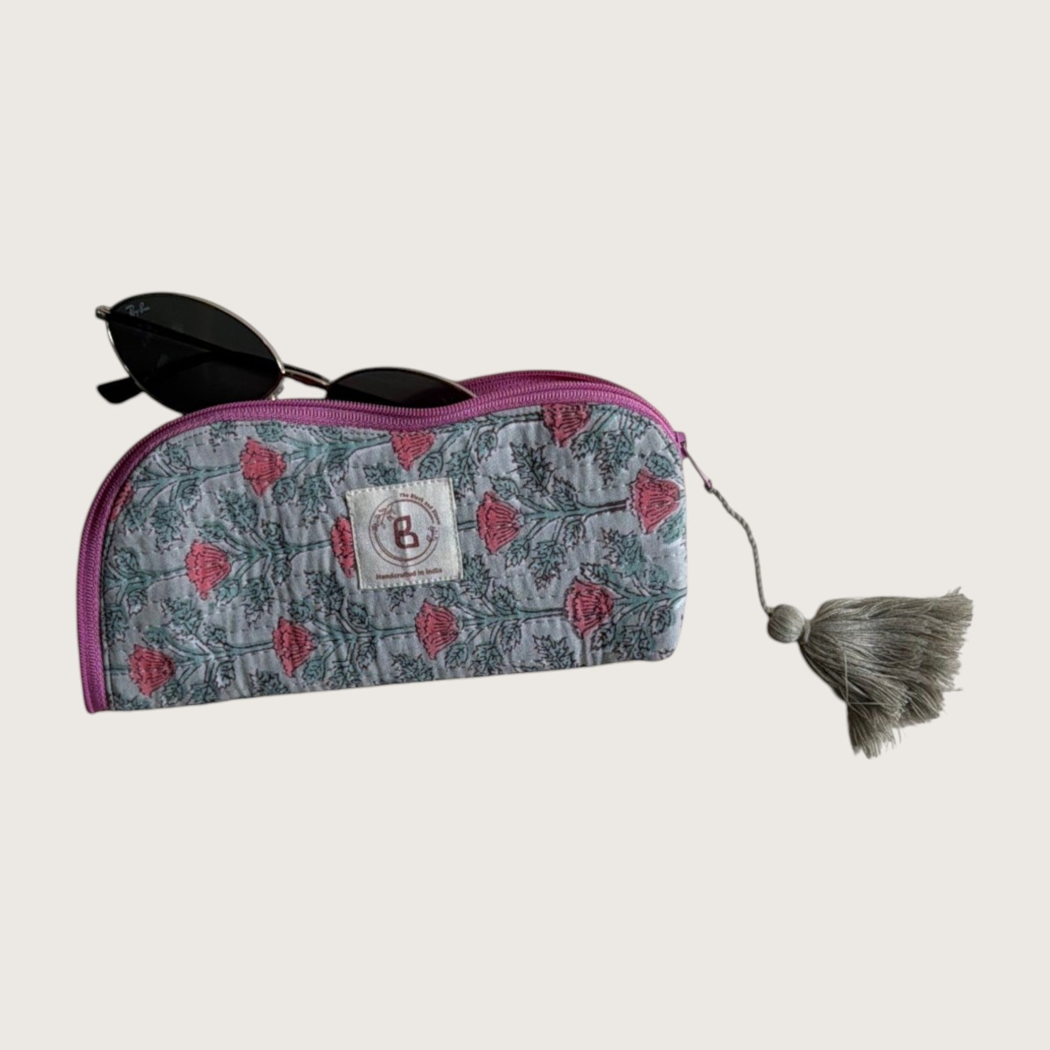 The Block & Bloom quilted cotton sunglasses pouch in sage green with pink floral vine print and a decorative tassel.