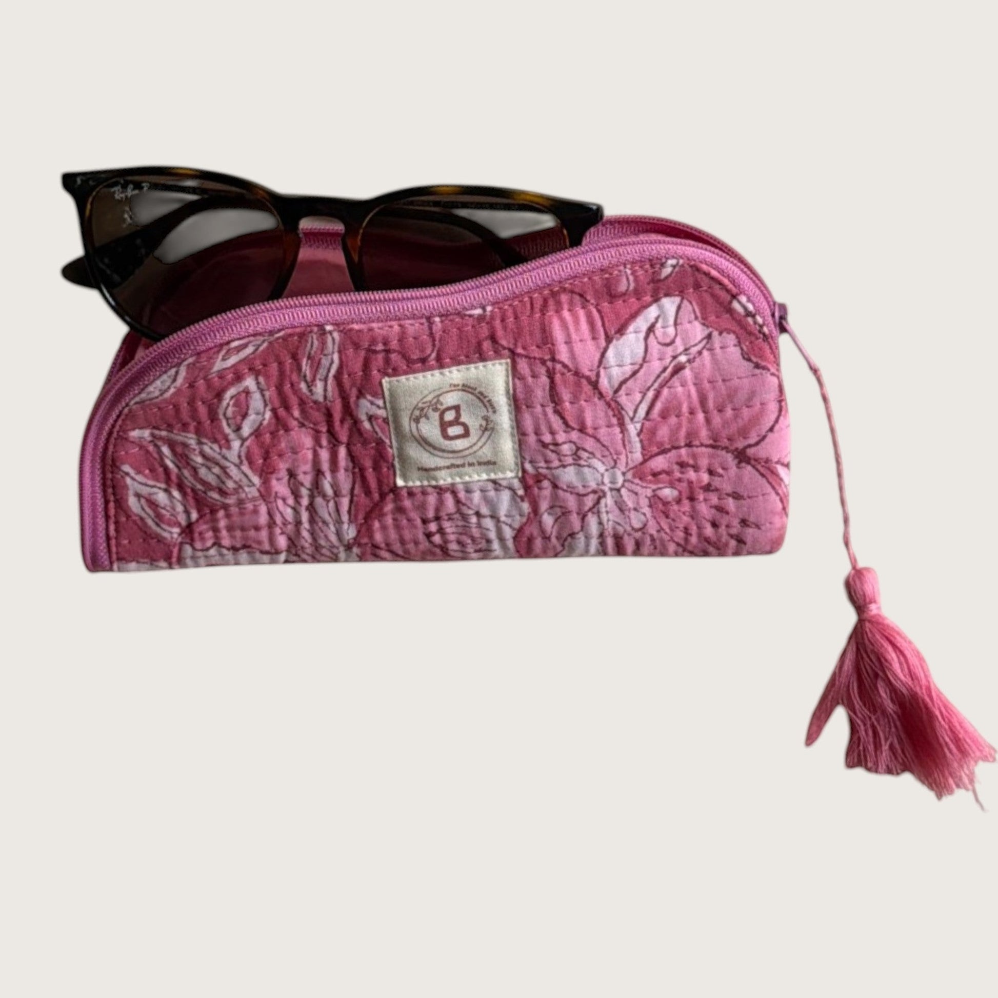 The Block & Bloom quilted cotton sunglasses pouch in pink with a white lily floral print and a decorative tassel.