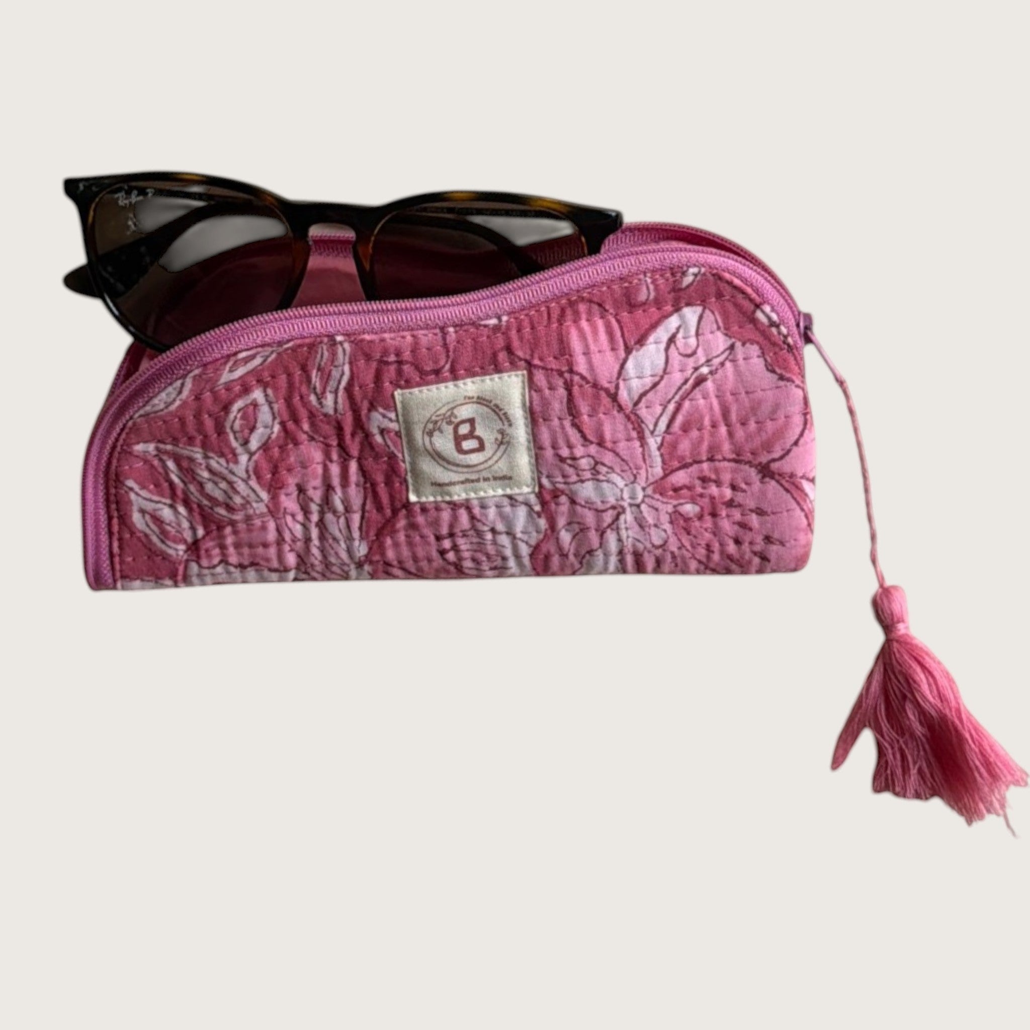 The Block & Bloom quilted cotton sunglasses pouch in pink with a white lily floral print and a decorative tassel.