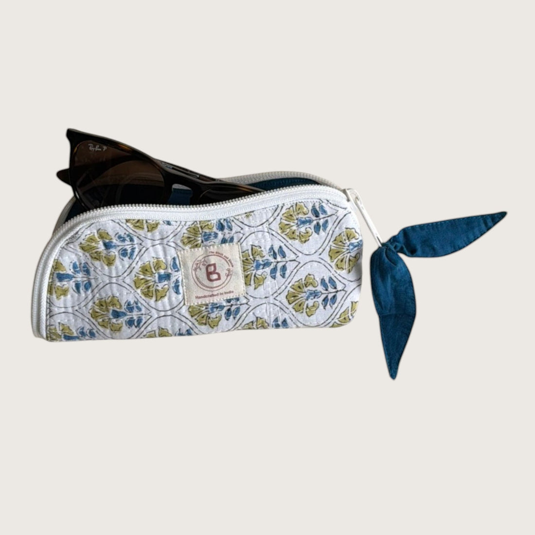 The Block & Bloom quilted cotton sunglasses pouch in white with blue and yellow cosmos floral print and zipper pull.