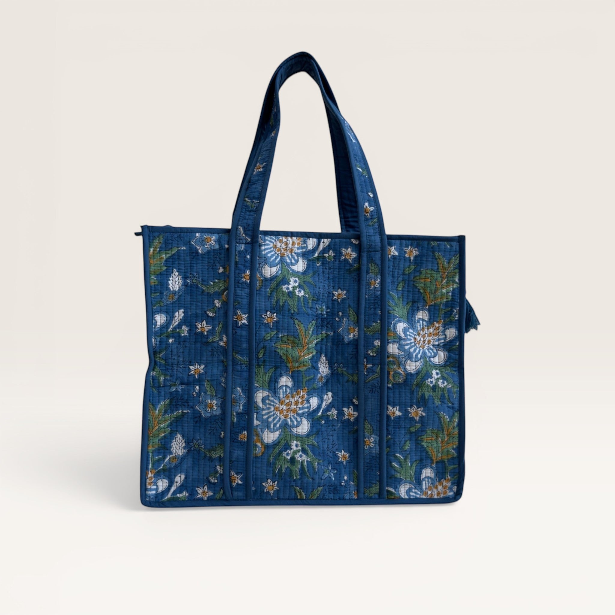 The Block & Bloom Gardenia Bloom quilted tote bag in cobalt blue with white floral block print and sturdy handles.