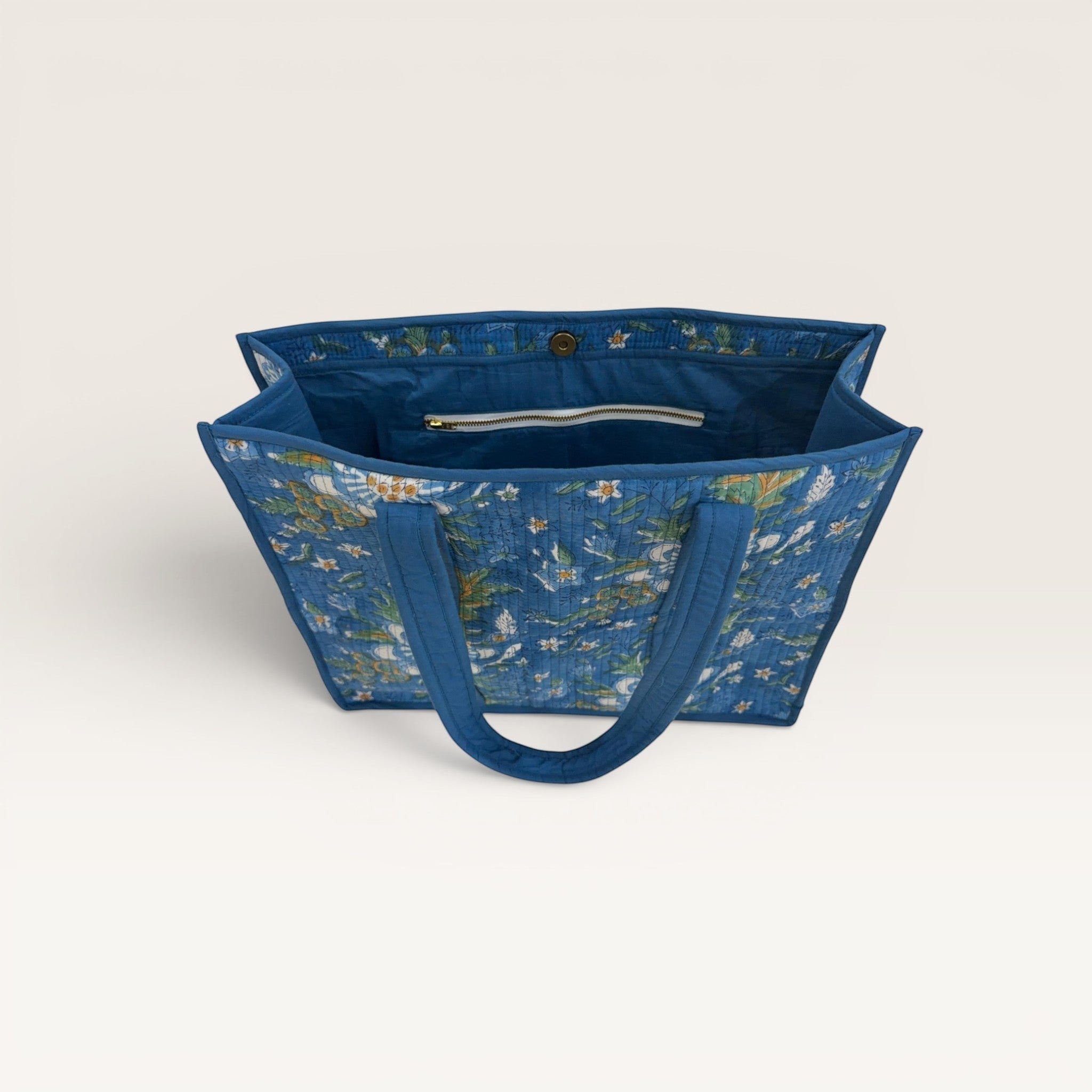 The Block & Bloom Gardenia Bloom quilted tote bag in cobalt blue with white floral print and interior zipper pocket.