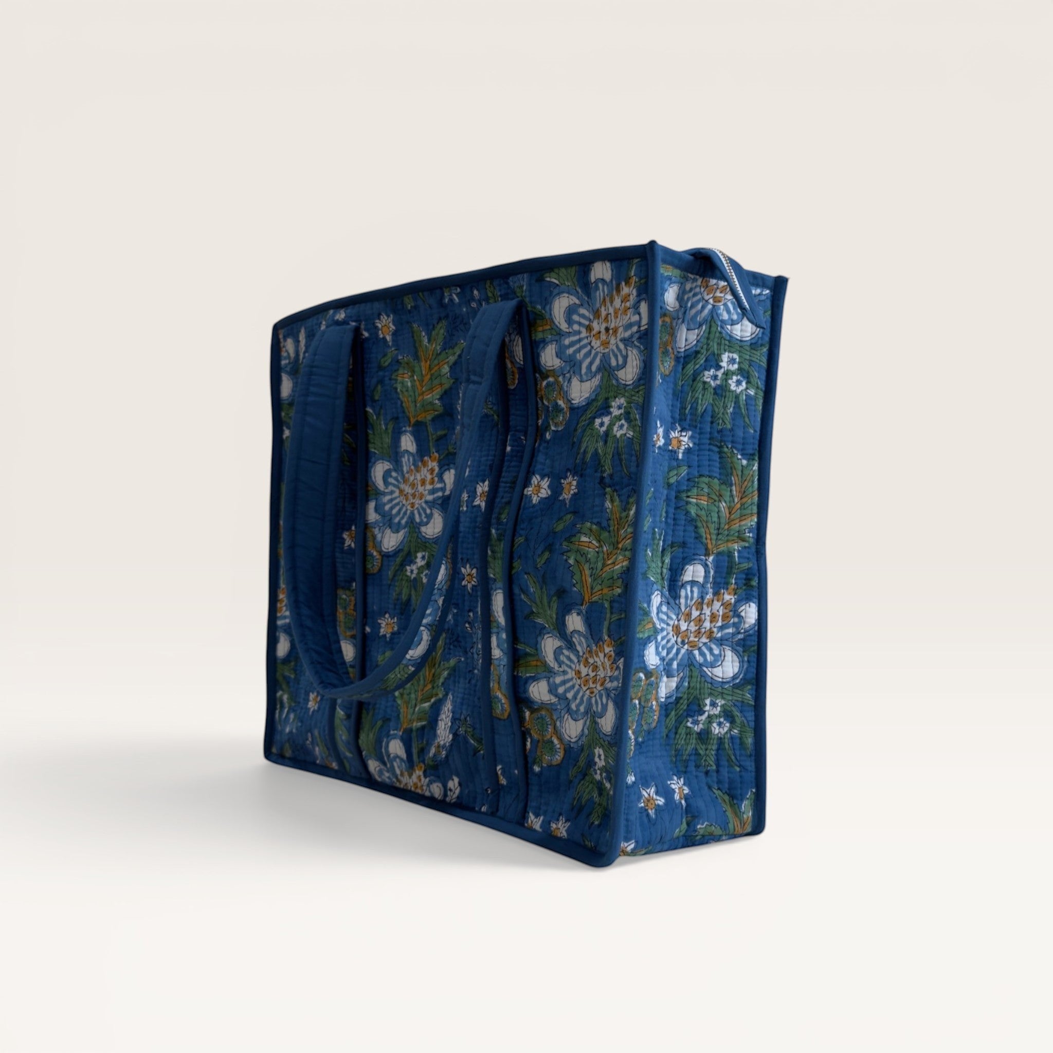 The Block & Bloom quilted tote bag in cobalt blue with white gardenia floral print and structured base, side view.