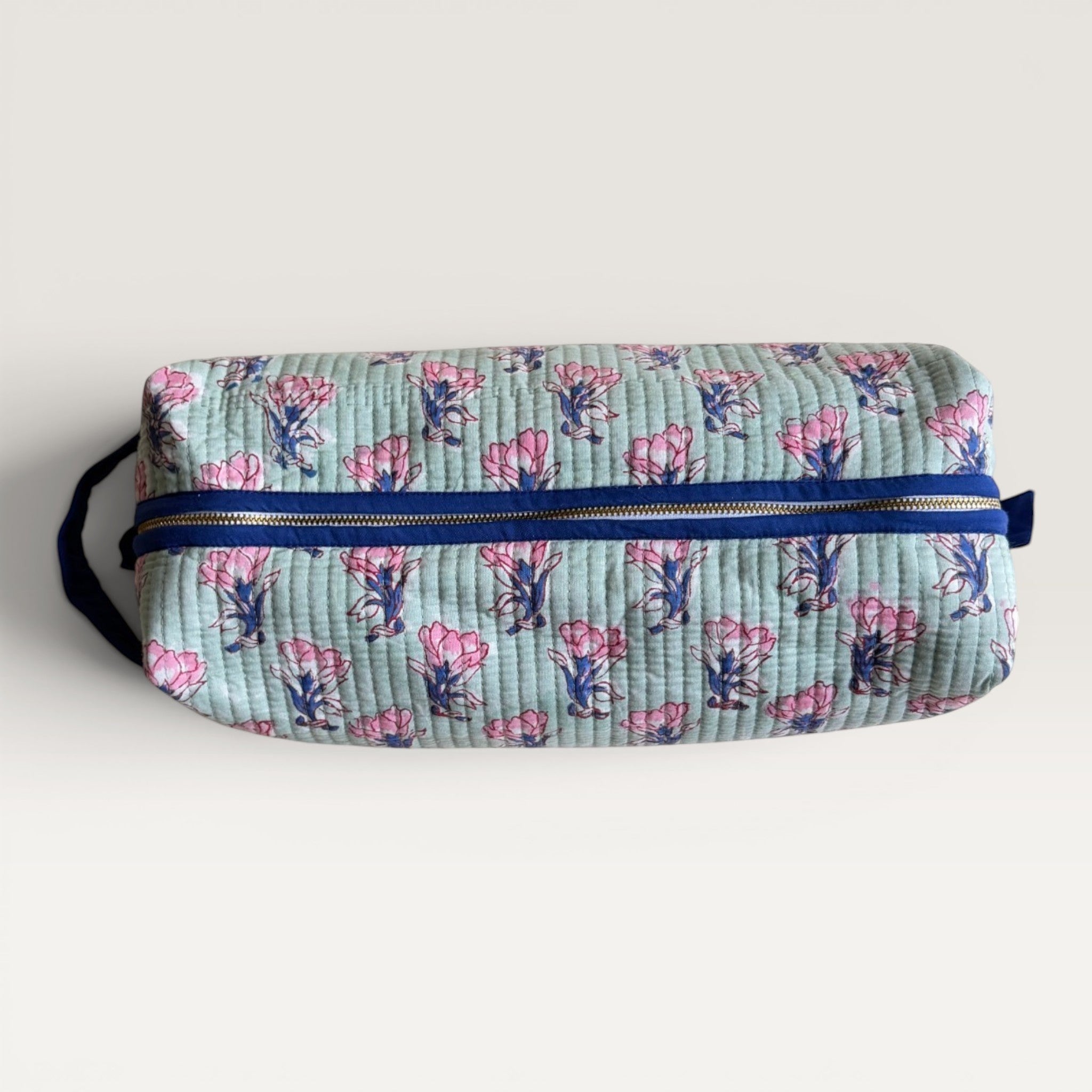 The Block & Bloom Saffron Sage quilted hair tool organizer bag with pink floral block print on sage green fabric.