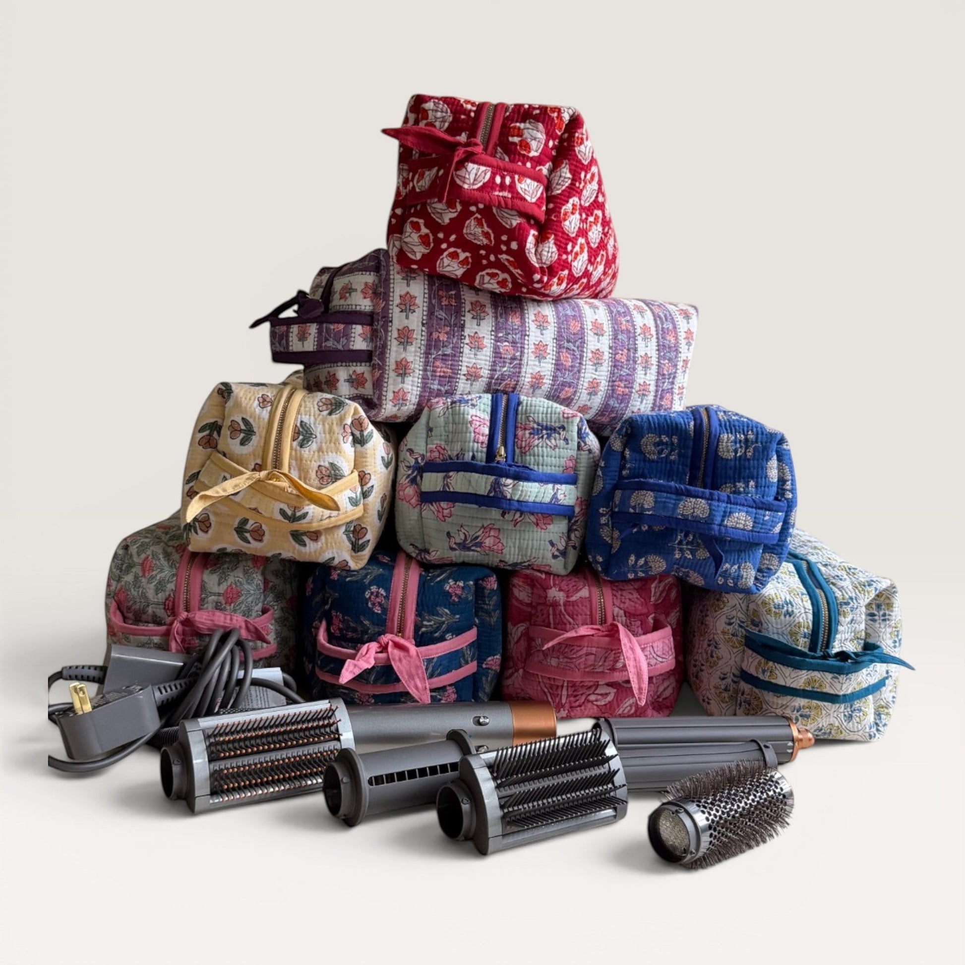 The Block & Bloom quilted hair tool organizer bags in various floral patterns stacked with Dyson styling attachments.