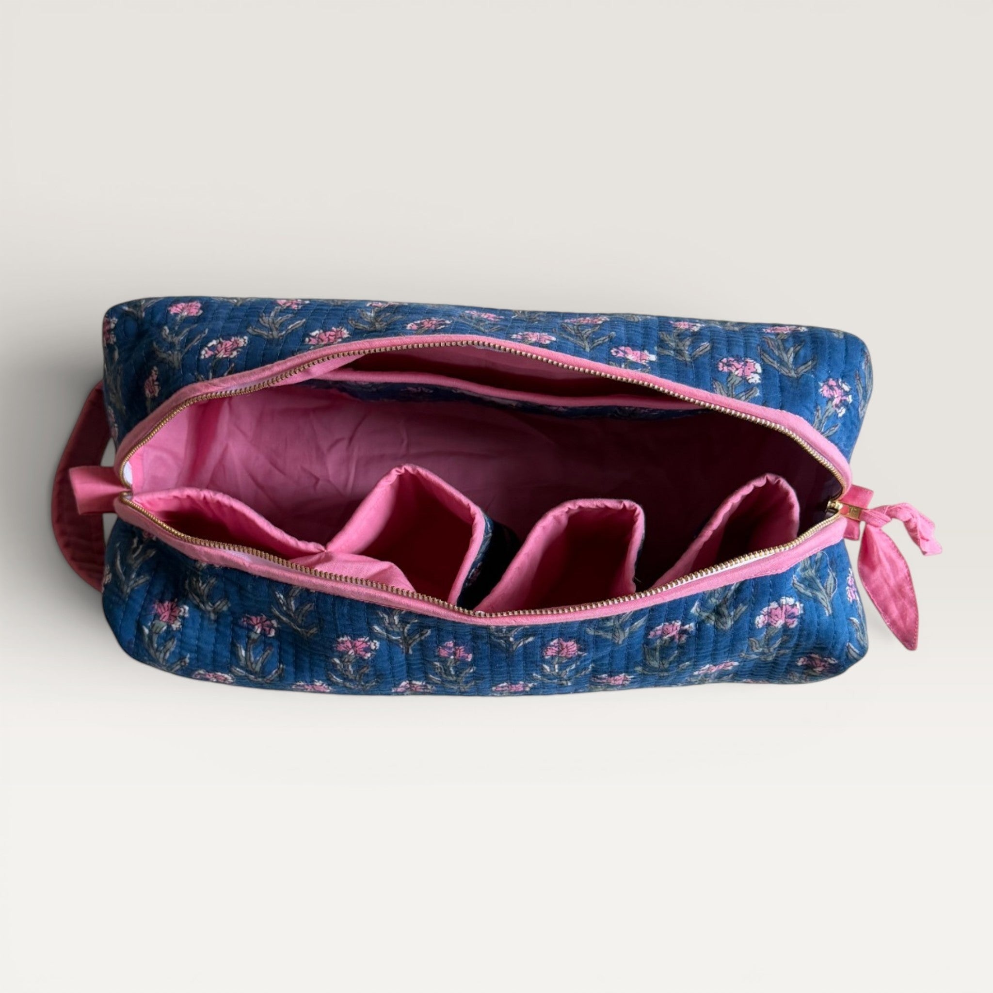 The Block & Bloom Pink Periwinkle quilted hair tool organizer bag in navy blue with pink floral print and open top.