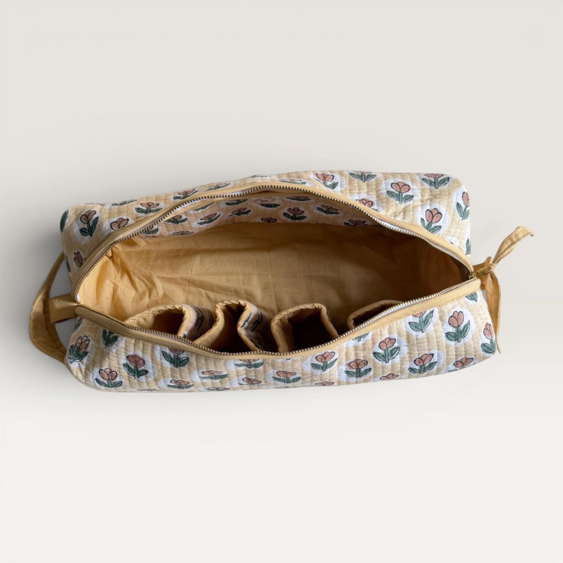 The Block & Bloom quilted hair tool organizer bag in golden yellow with a rust tulip print and interior storage slots.