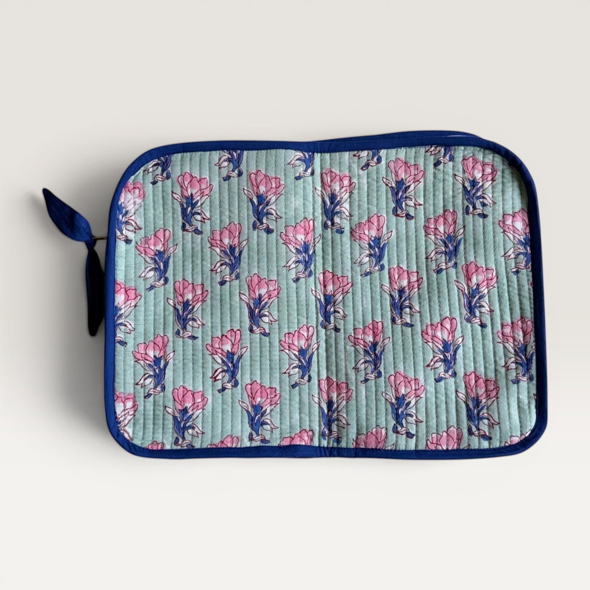 The Block & Bloom quilted laptop sleeve in sage green with pink saffron flower block print and navy blue trim.