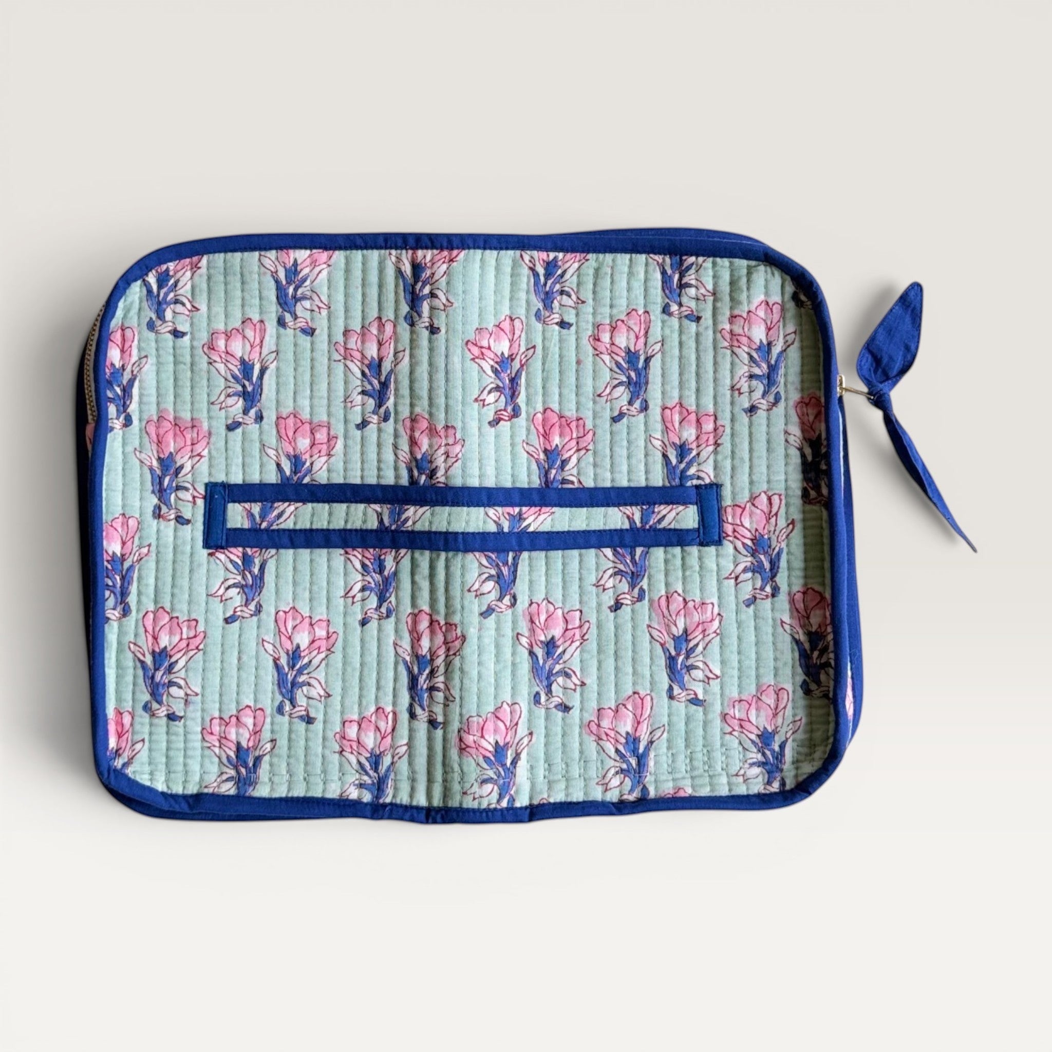 The Block & Bloom quilted laptop sleeve in sage green with pink saffron flower print and navy blue trim.