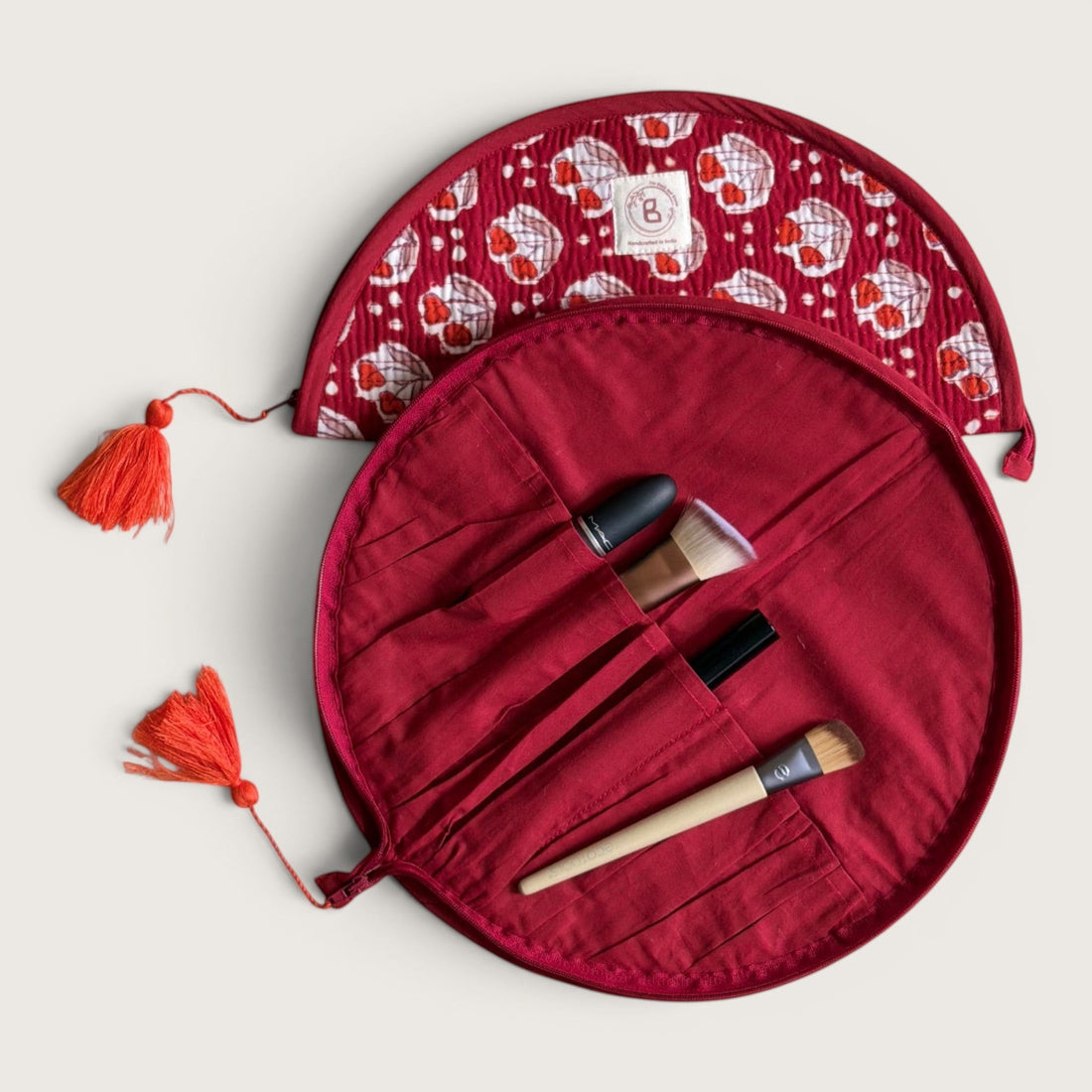 The Block & Bloom quilted makeup brush pouch in burgundy red with red tulip motifs, white dots, and tassel zippers.