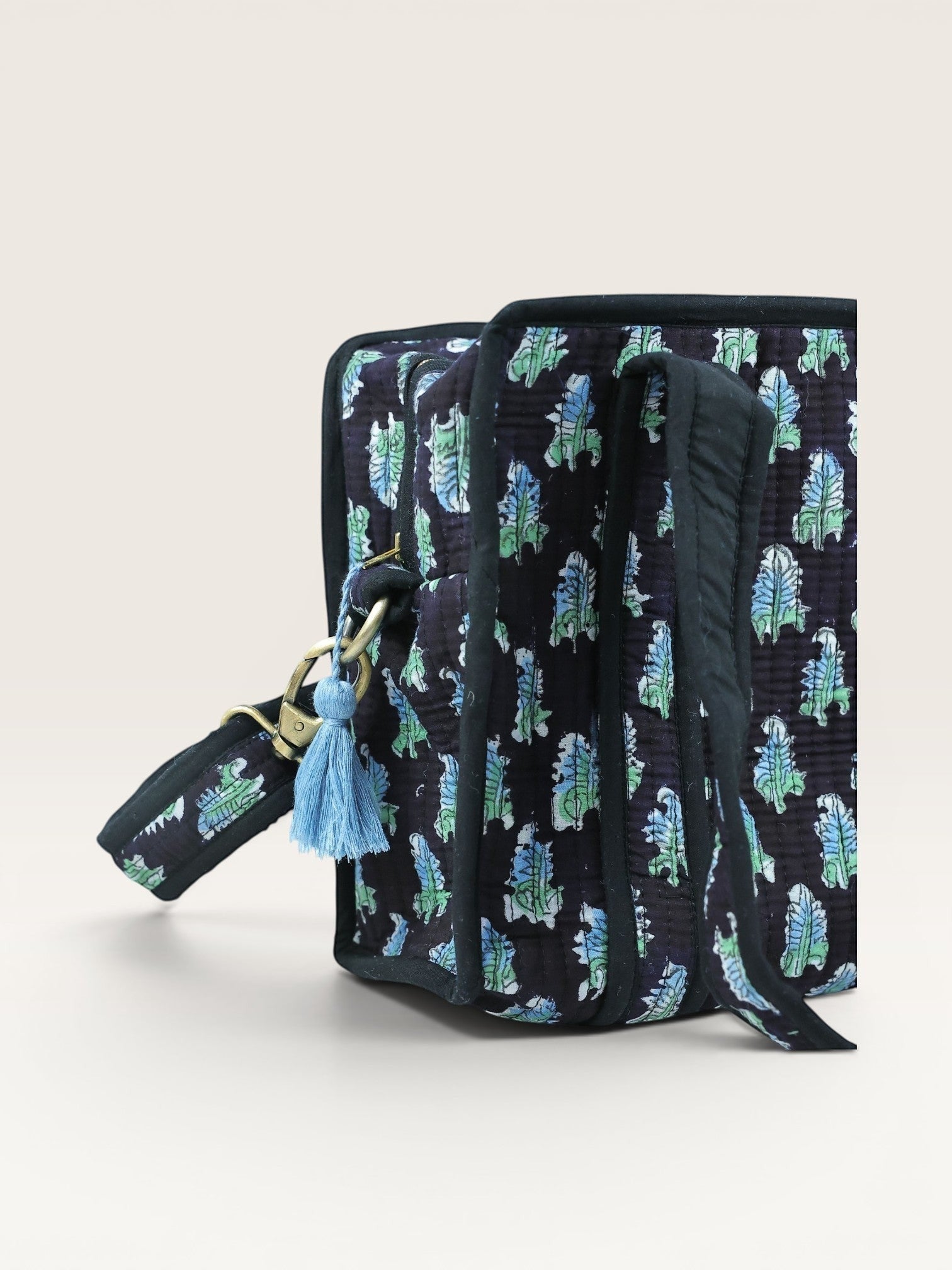 The Block & Bloom Midnight Fern quilted mini tote with blue and sage green leaf print on black fabric and brass clasp.