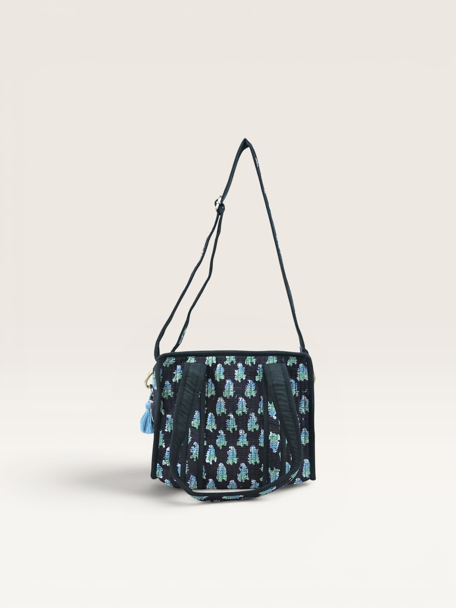 The Block & Bloom Midnight Fern quilted mini tote bag in black with blue and sage green leaf print and shoulder strap.