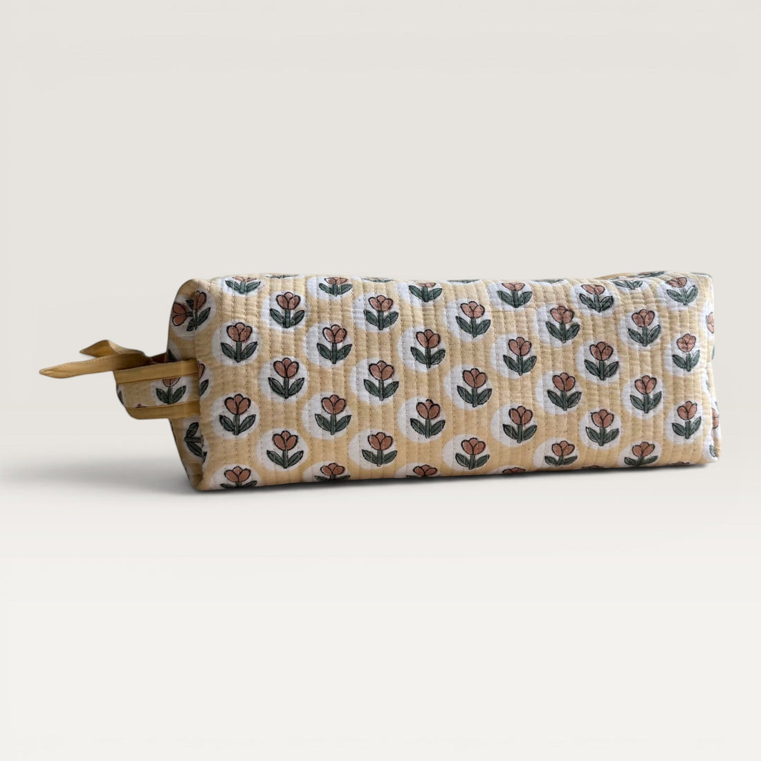 The Block & Bloom quilted hair tool organizer bag in golden yellow with a rust brown tulip block-print pattern.